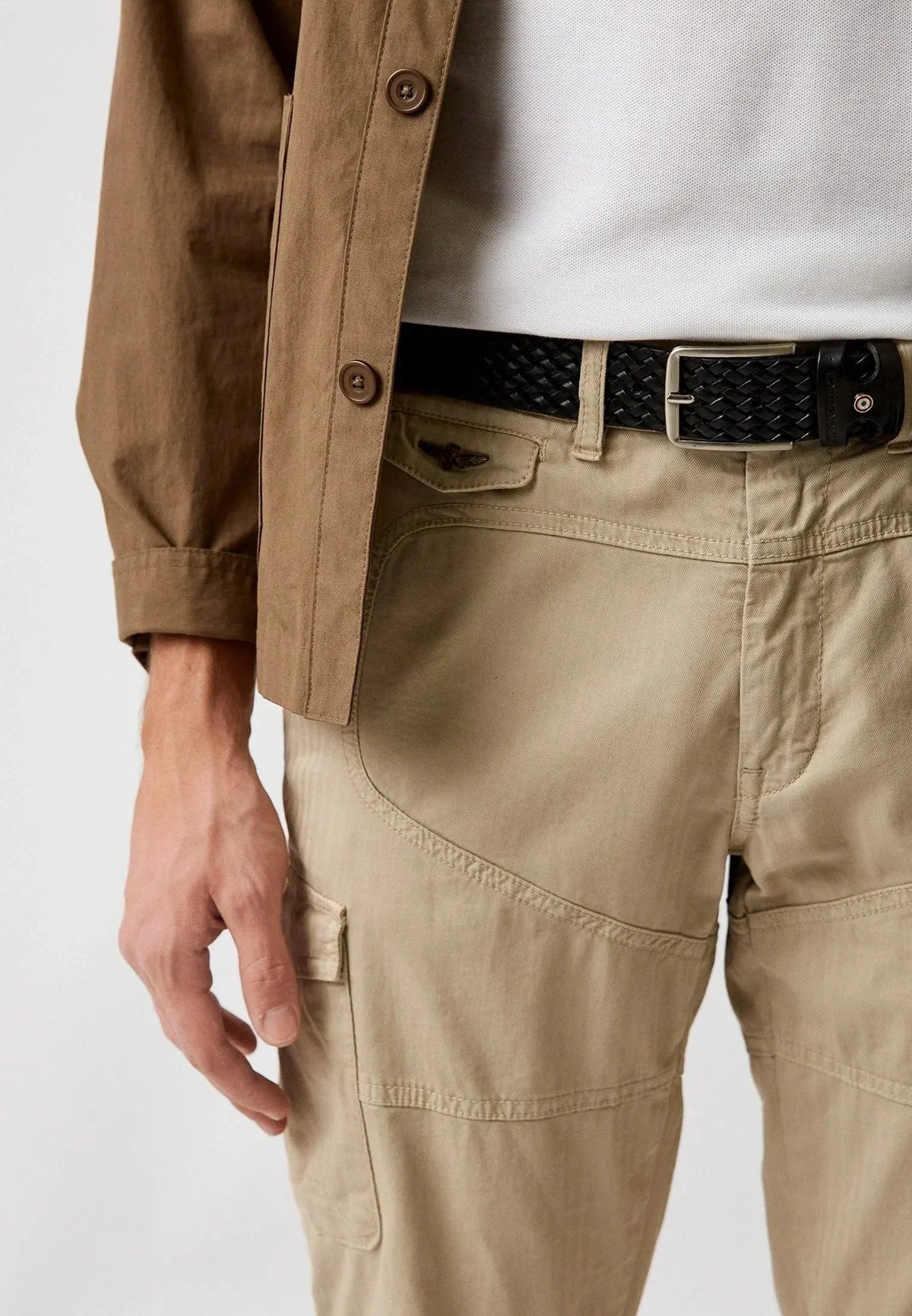 Pantaloni cargo uomo beige con cintura intrecciata nera e giacca marrone, stile casual elegante