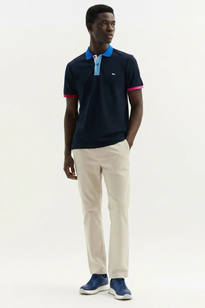 Modello con polo blu con colletto azzurro, pantaloni beige e sneakers blu, moda uomo casual.