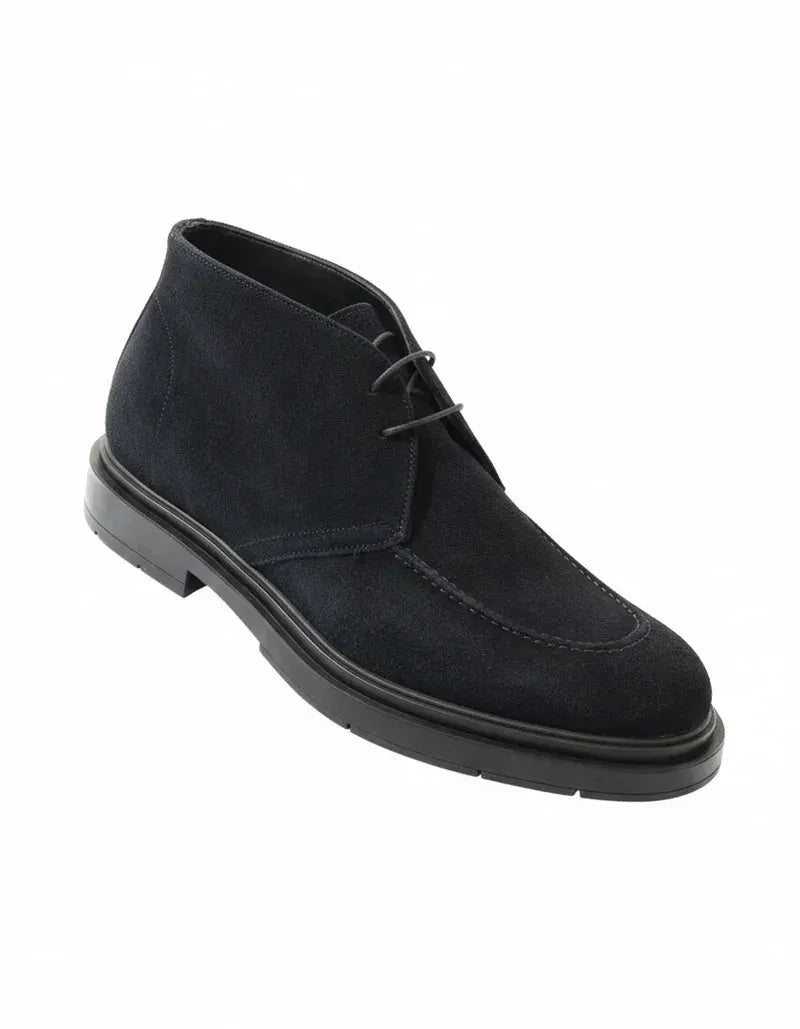 Stivaletto chukka uomo in camoscio blu con suola nera, elegante e moderno su sfondo bianco.