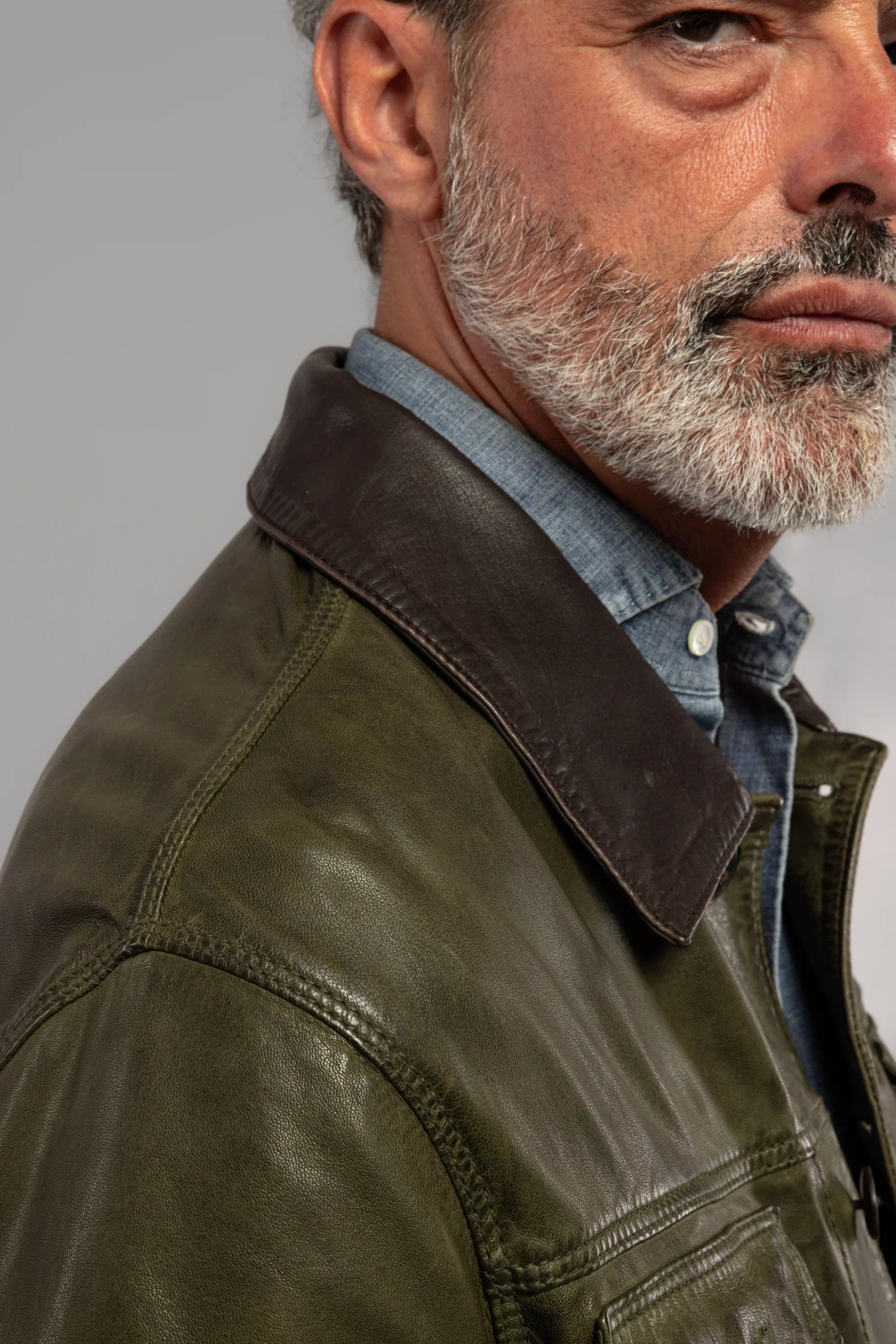 Giacca uomo in pelle verde con colletto marrone, camicia denim, dettaglio spalla