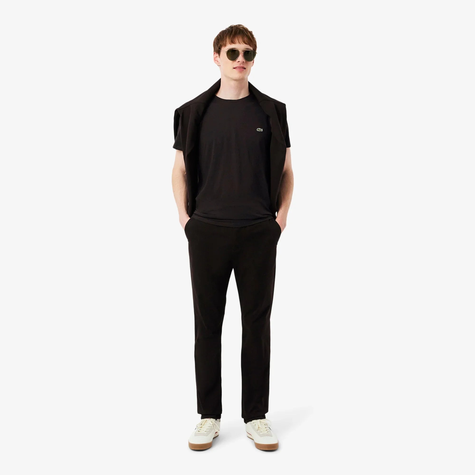 Modello uomo con t-shirt nera, pantaloni neri e scarpe bianche, stile casual elegante