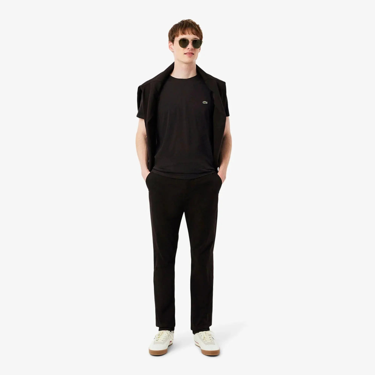 Modello uomo con t-shirt nera, pantaloni neri e scarpe bianche, stile casual elegante