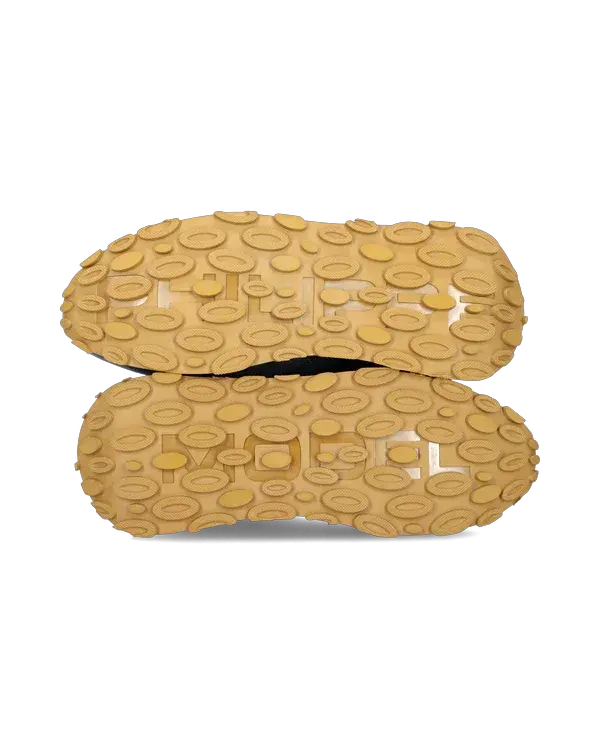 Suole scarpe sportive gialle con motivo antiscivolo a rilievo, fondo isolato su bianco.