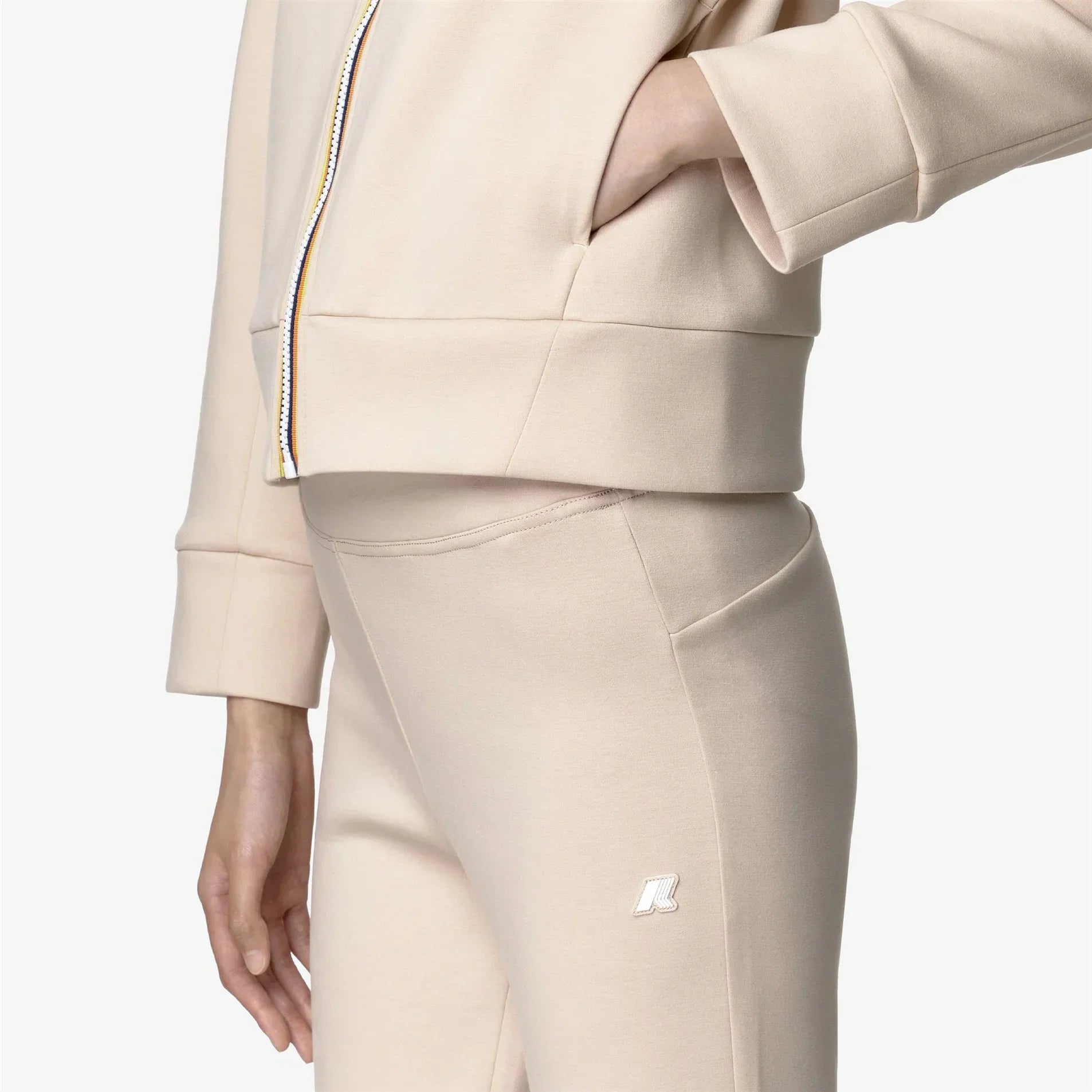 Tuta donna beige in cotone con logo ricamato su pantalone, dettaglio zip giacca.