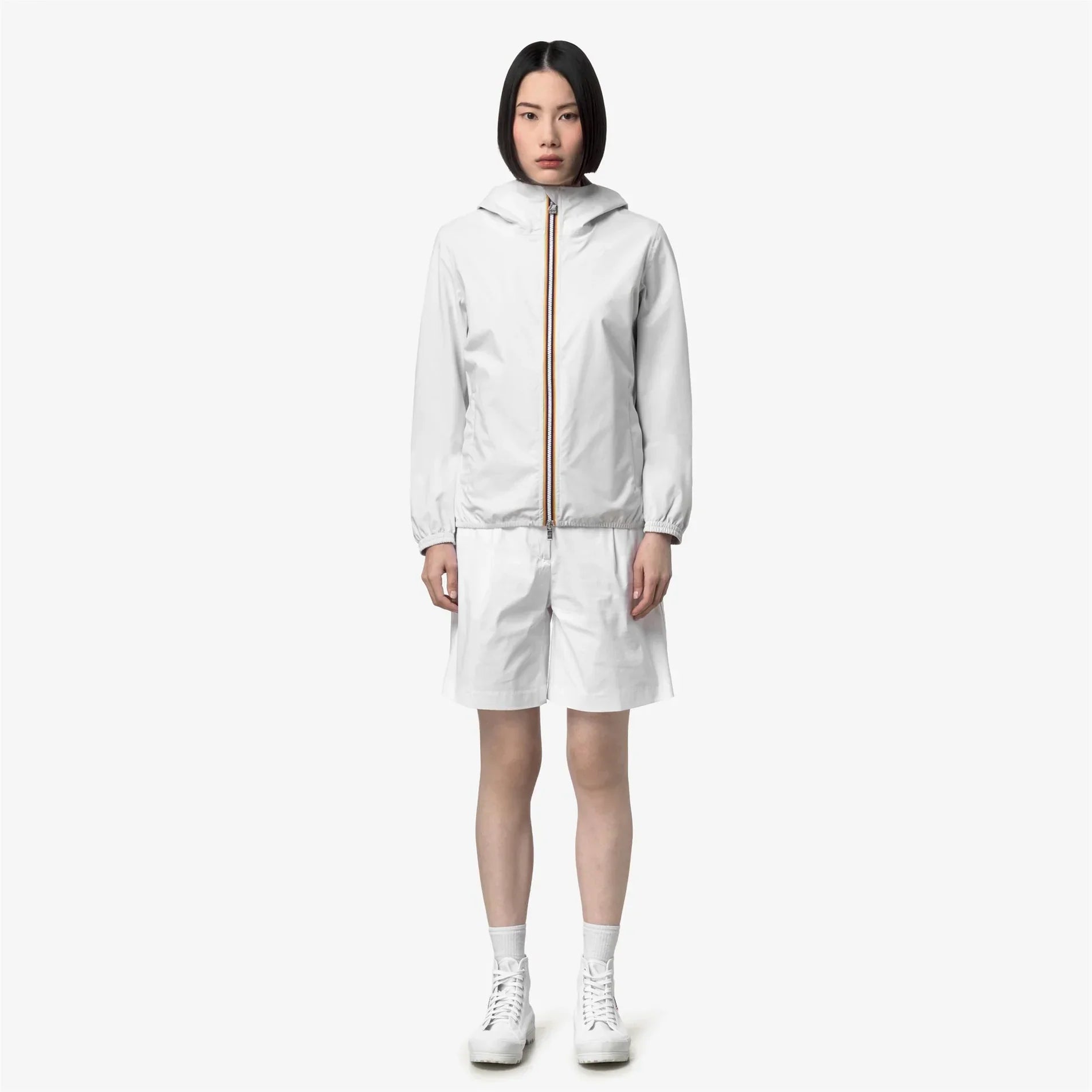 Donna con giacca leggera bianca con cappuccio e pantaloncini, moda abbigliamento donna elegante