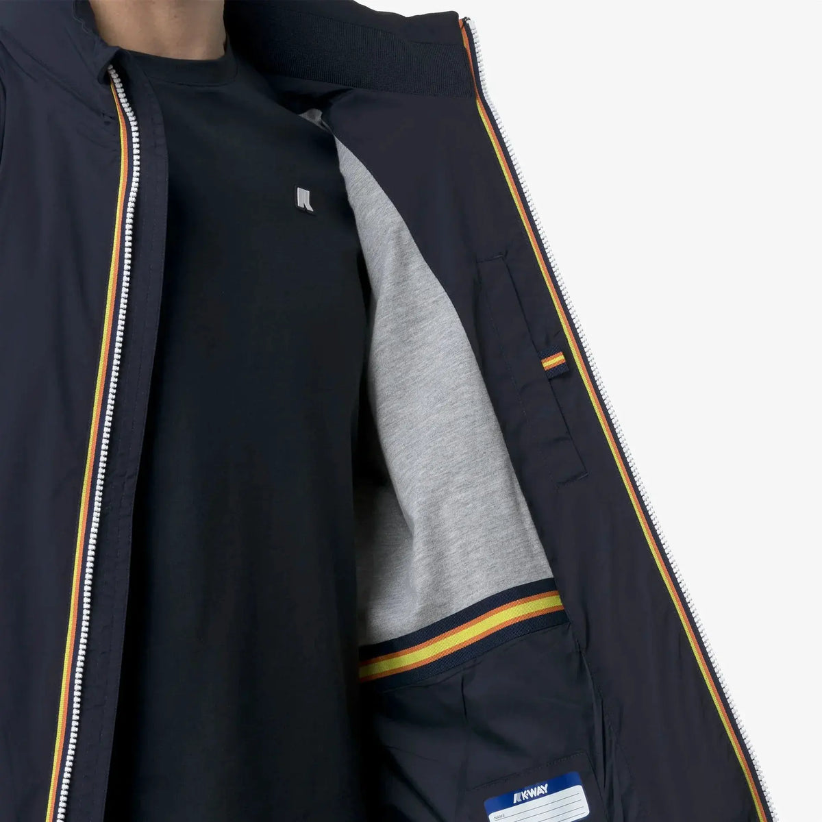 Dettaglio interno giacca uomo blu con zip e fodera grigia, bordo a righe colorate
