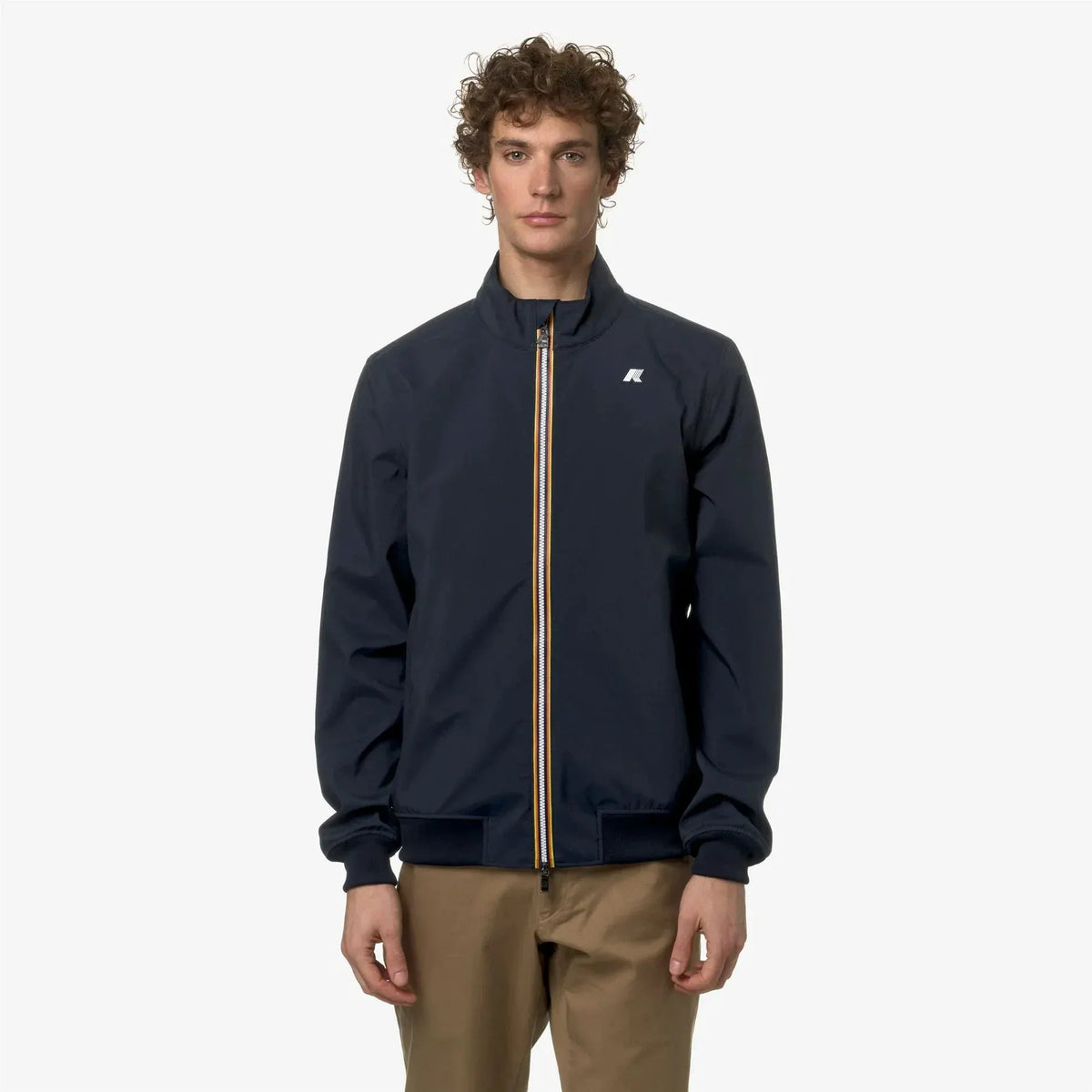 Giacca uomo blu scuro con zip a contrasto e pantaloni beige, moda casual elegante