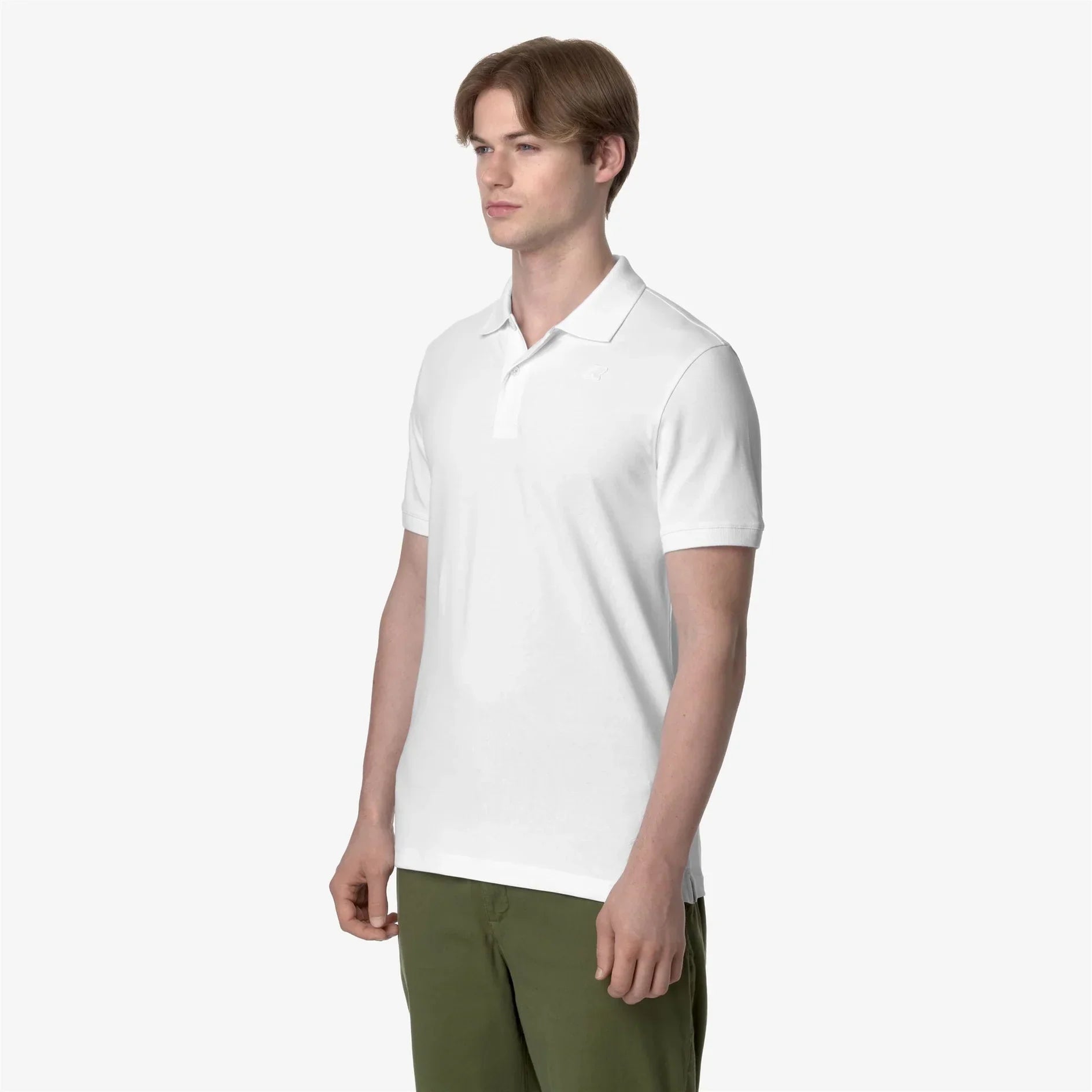 modello indossa polo bianca uomo manica corta su pantaloni verdi, sfondo neutro
