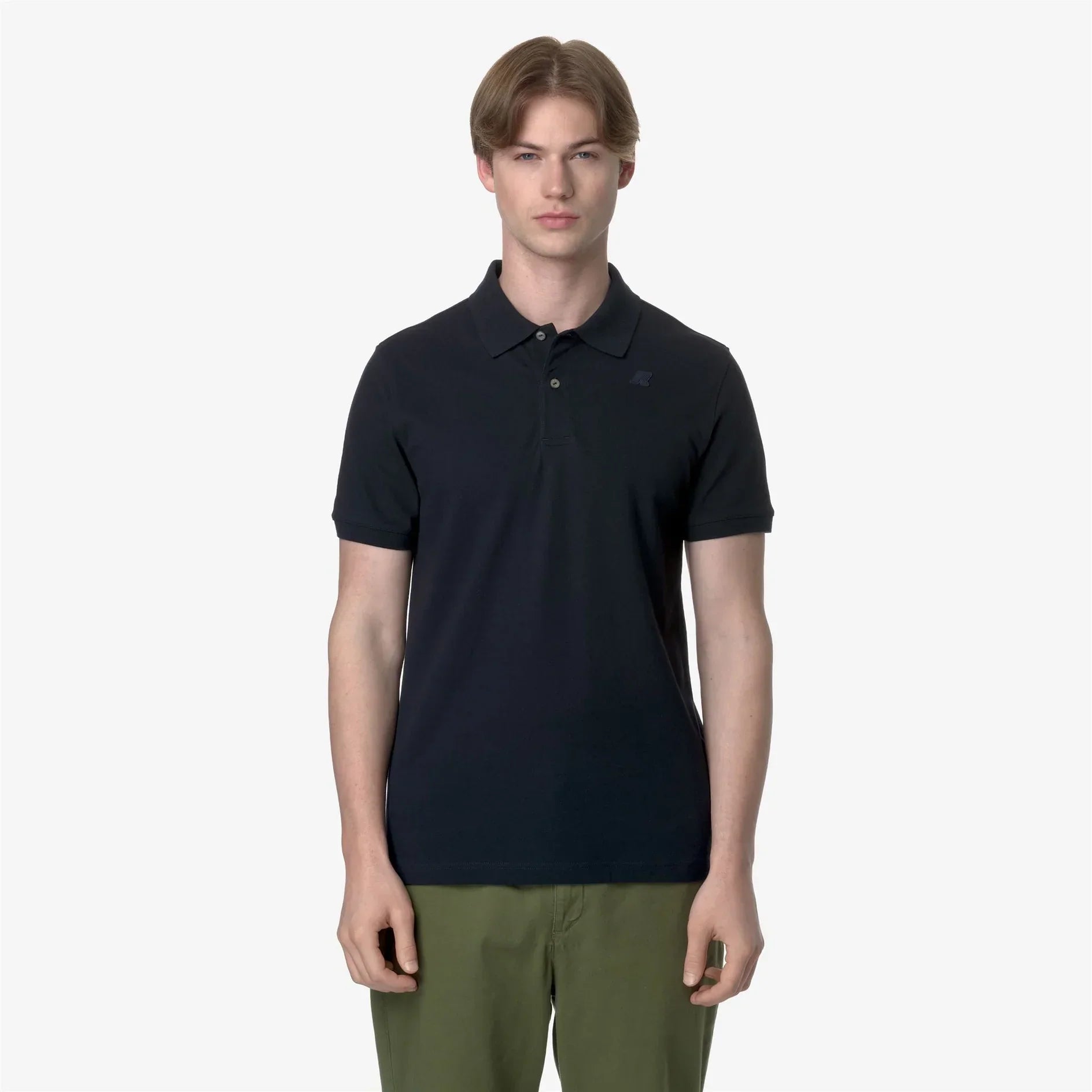 Uomo indossa polo nera a manica corta e pantaloni verdi, abbigliamento casual elegante.