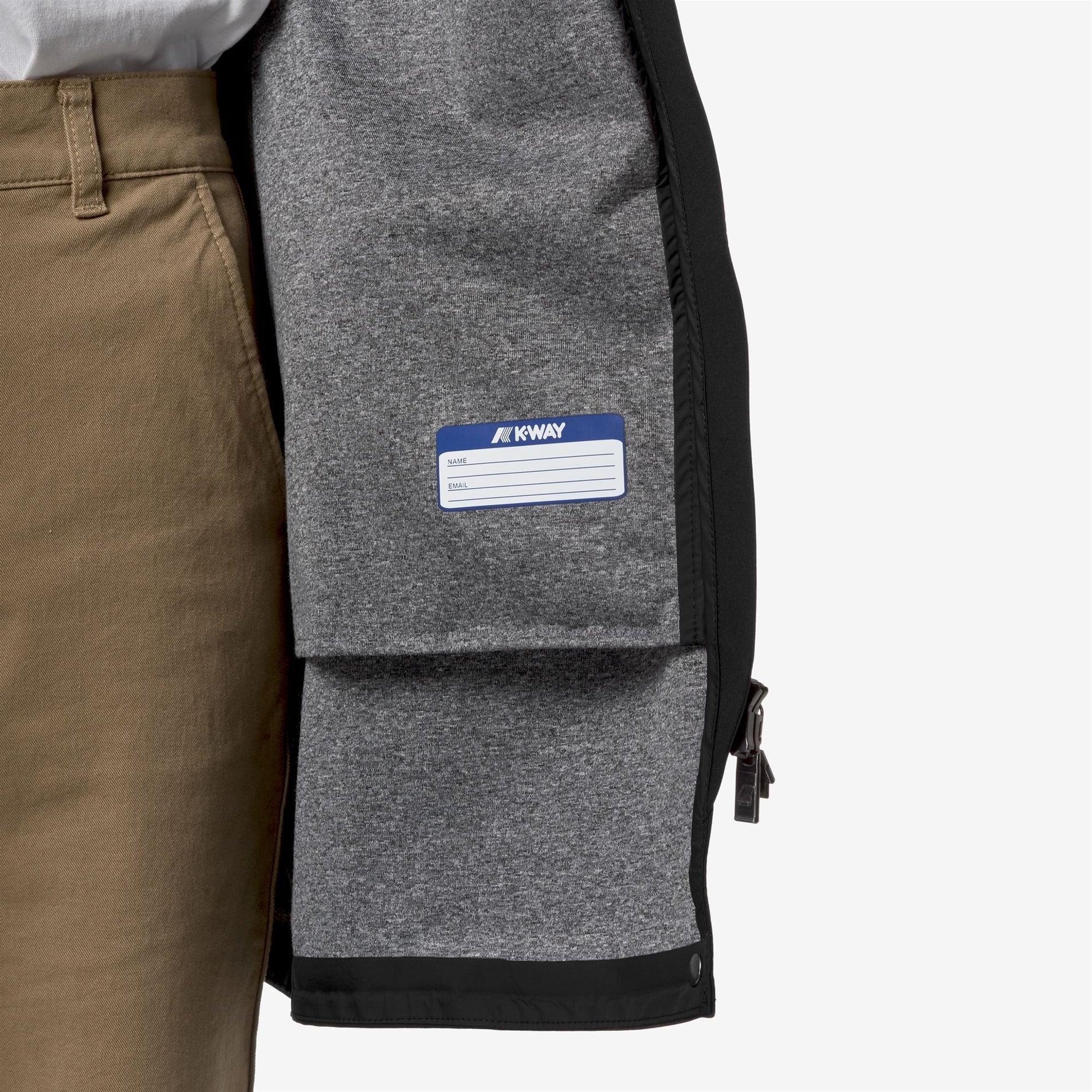 Interno giacca K-Way grigia con etichetta, dettaglio zip, pantalone beige uomo
