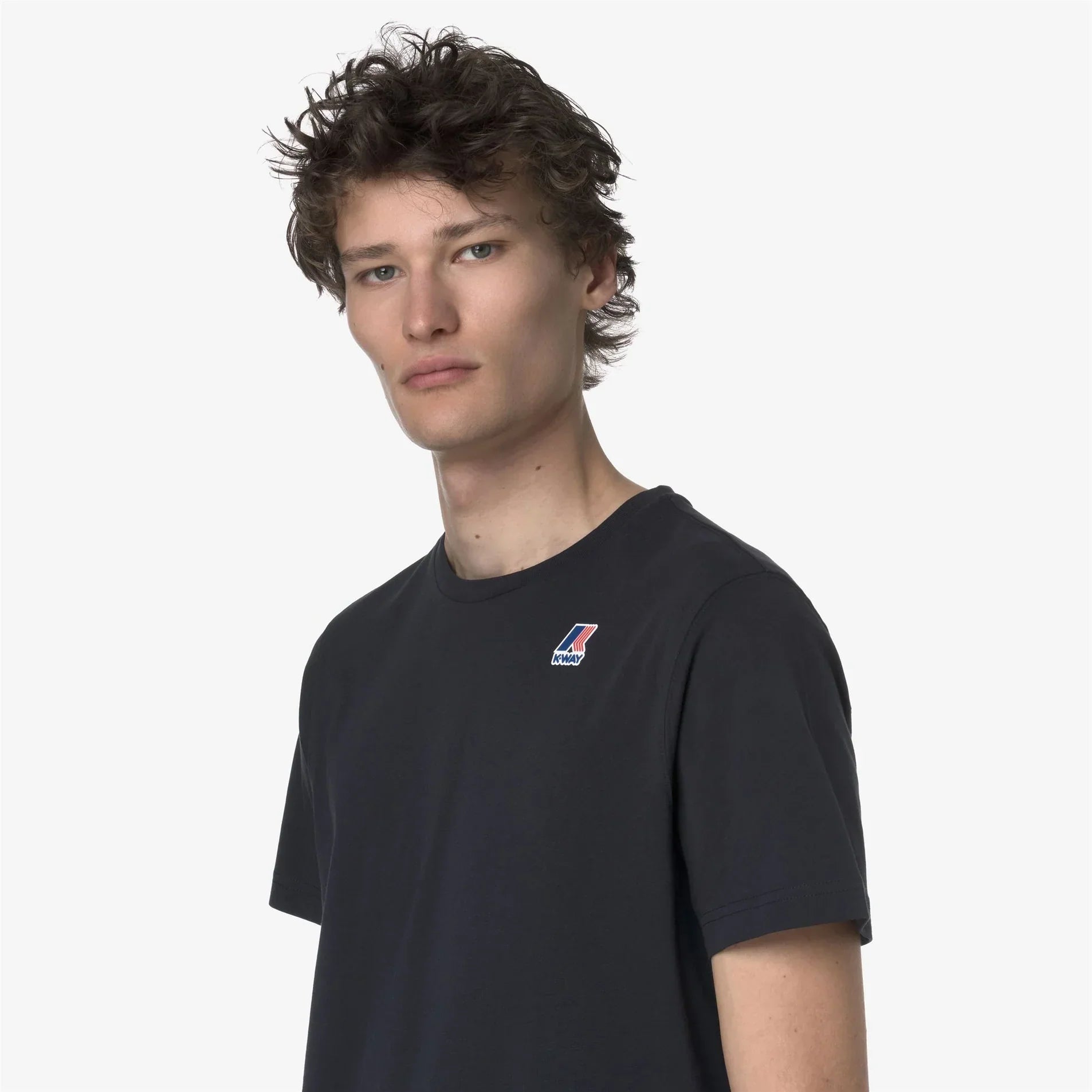 Modello indossa t-shirt nera K-Way da uomo con logo piccolo sul petto, moda casual