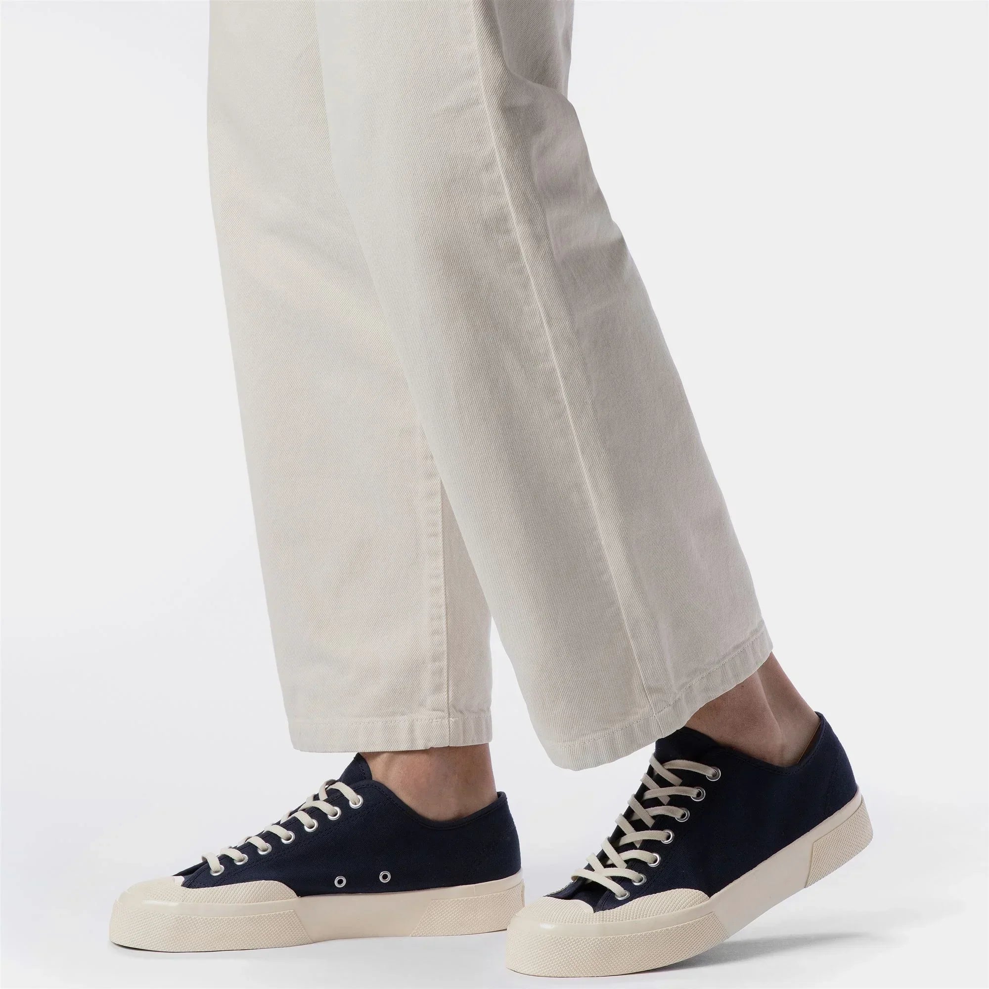 Sneakers uomo blu e panna in tela con suola alta, abbinate a pantaloni chiari, moda casual.