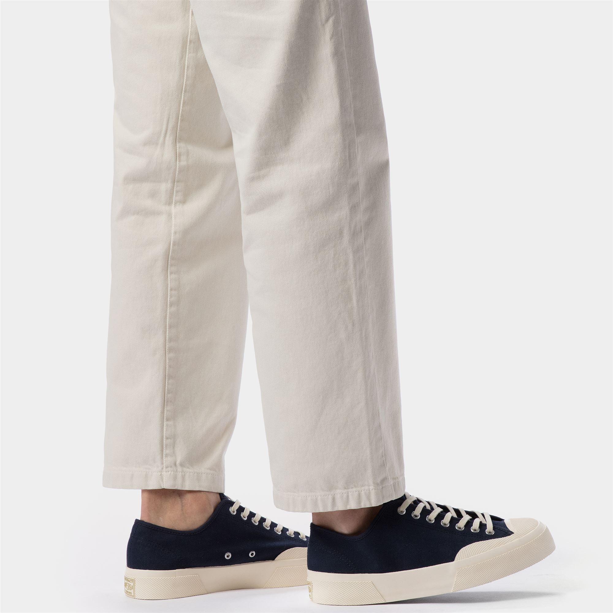 Sneakers nere da uomo in tela con suola bianca e pantaloni chiari, moda casual