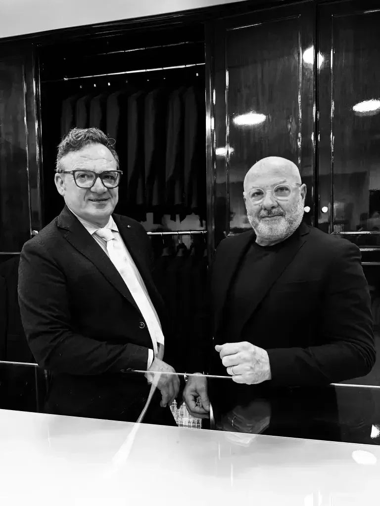 Due uomini eleganti in negozio di abbigliamento uomo, giacche e camicie sullo sfondo.