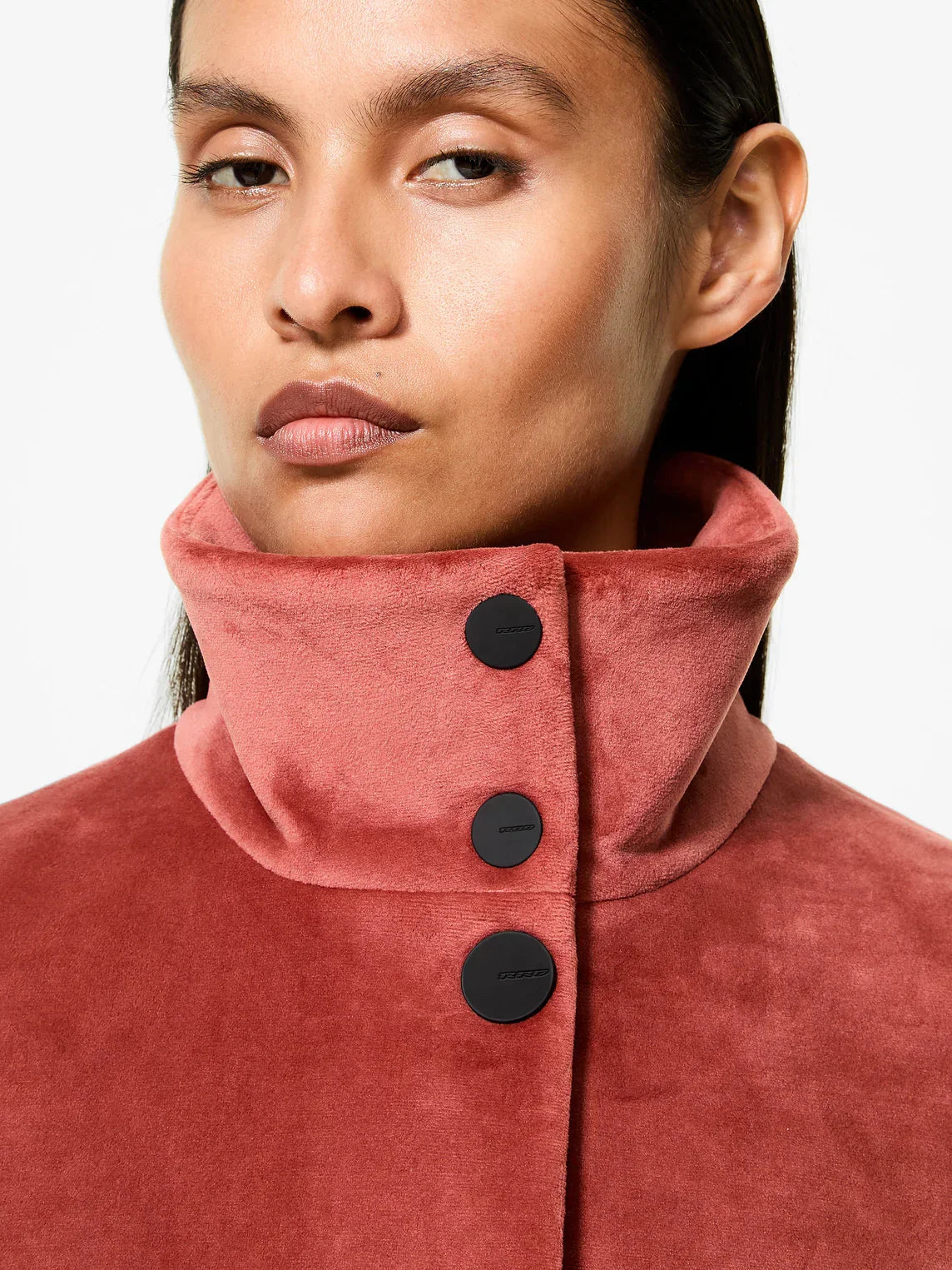 Primo piano di donna con cappotto rosa in suede e colletto alto con bottoni neri