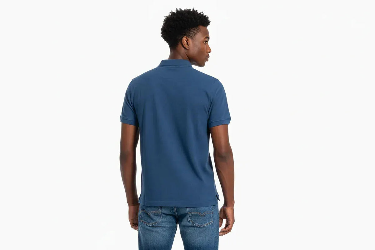 Uomo di spalle con polo blu a maniche corte e jeans, abbigliamento casual