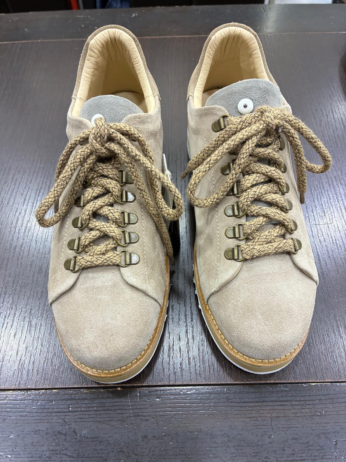 Scarpe uomo in camoscio beige con lacci intrecciati, stile casual, su tavolo scuro