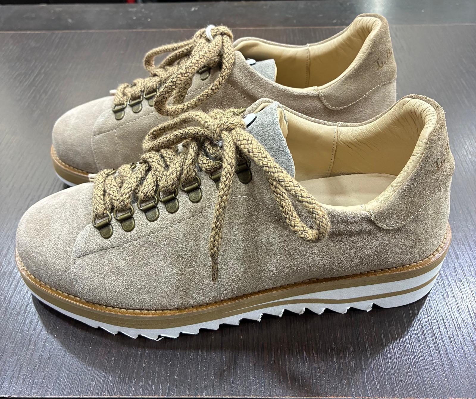 Scarpe uomo in camoscio beige con suola dentellata bianca, lacci intrecciati, stile casual elegante.