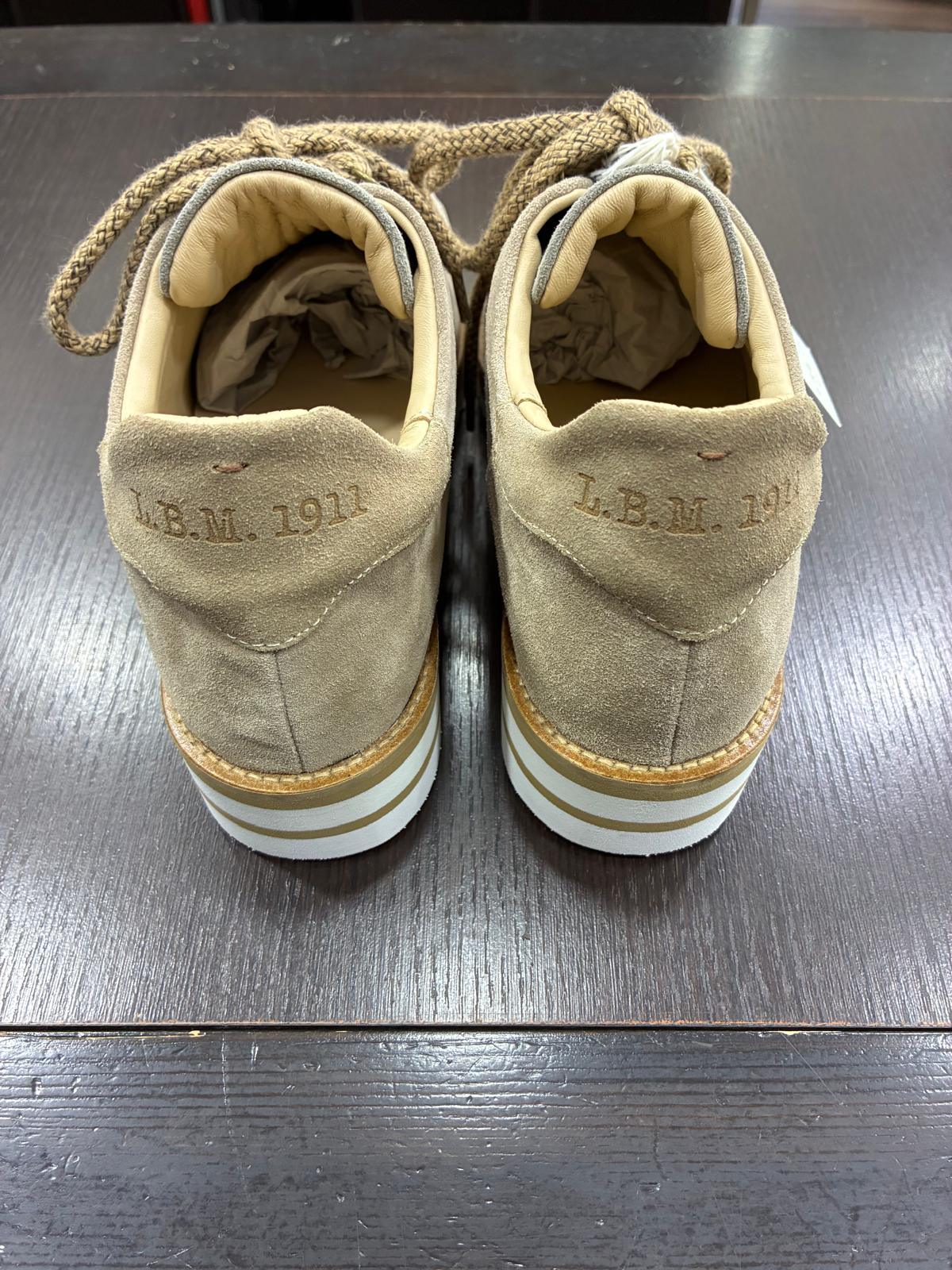 Scarpe sportive uomo in suede beige L.B.M. 1911 con suola a righe, viste da dietro su tavolo scuro