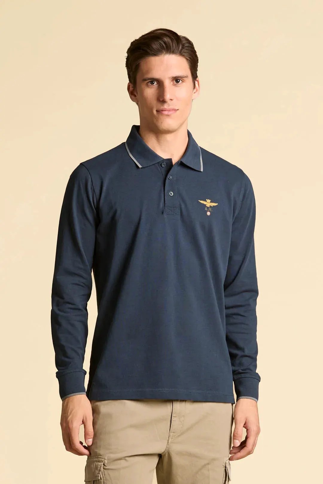 Polo uomo manica lunga blu navy con logo ricamato e colletto a contrasto su sfondo neutro.