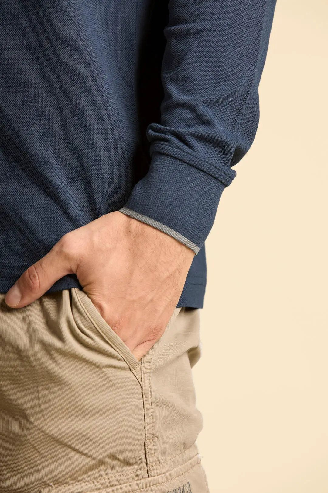Dettaglio di polo uomo blu navy manica lunga e pantaloni beige in tessuto leggero