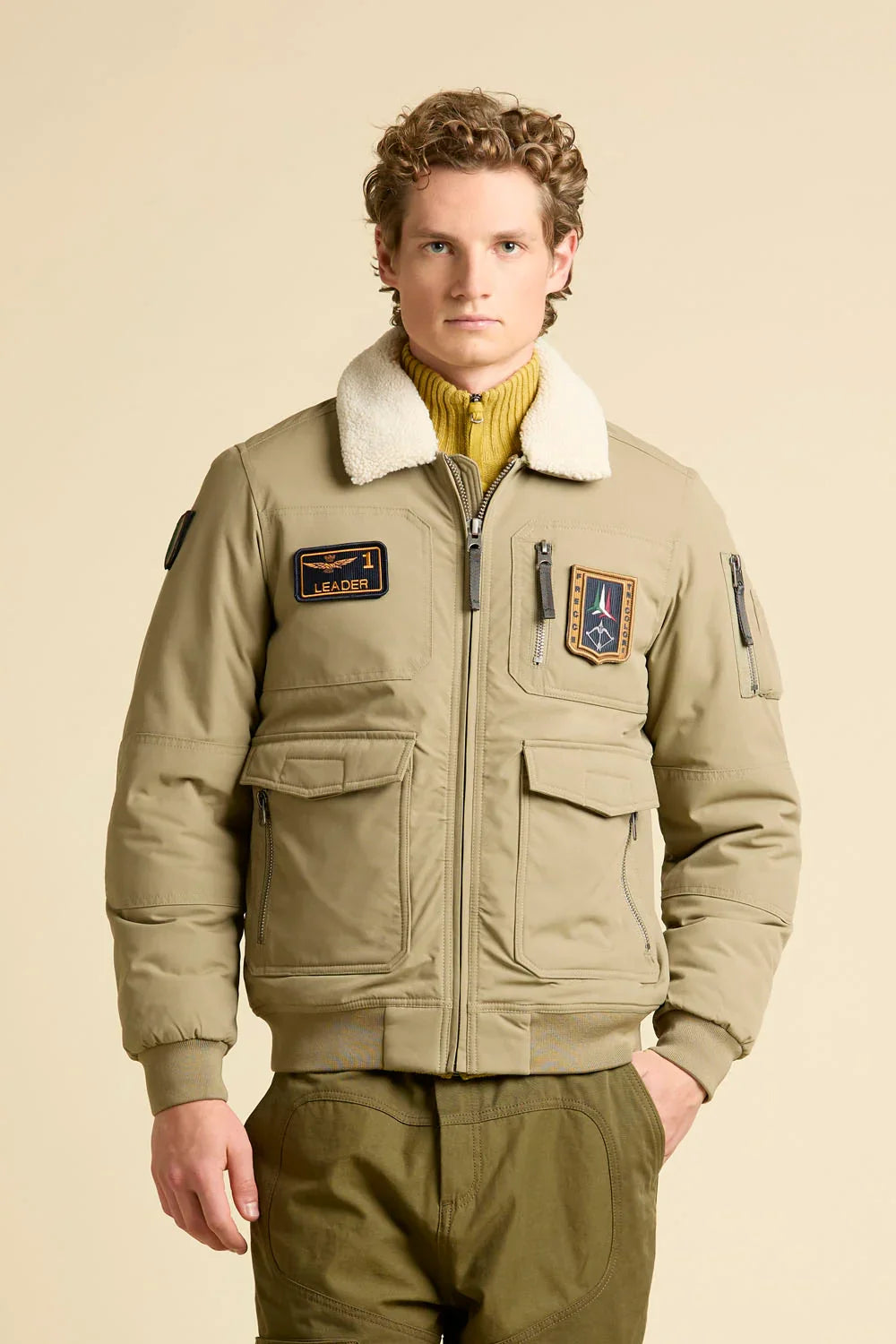 Giubbotto pilot beige con colletto in shearling e patch, moda uomo casual.