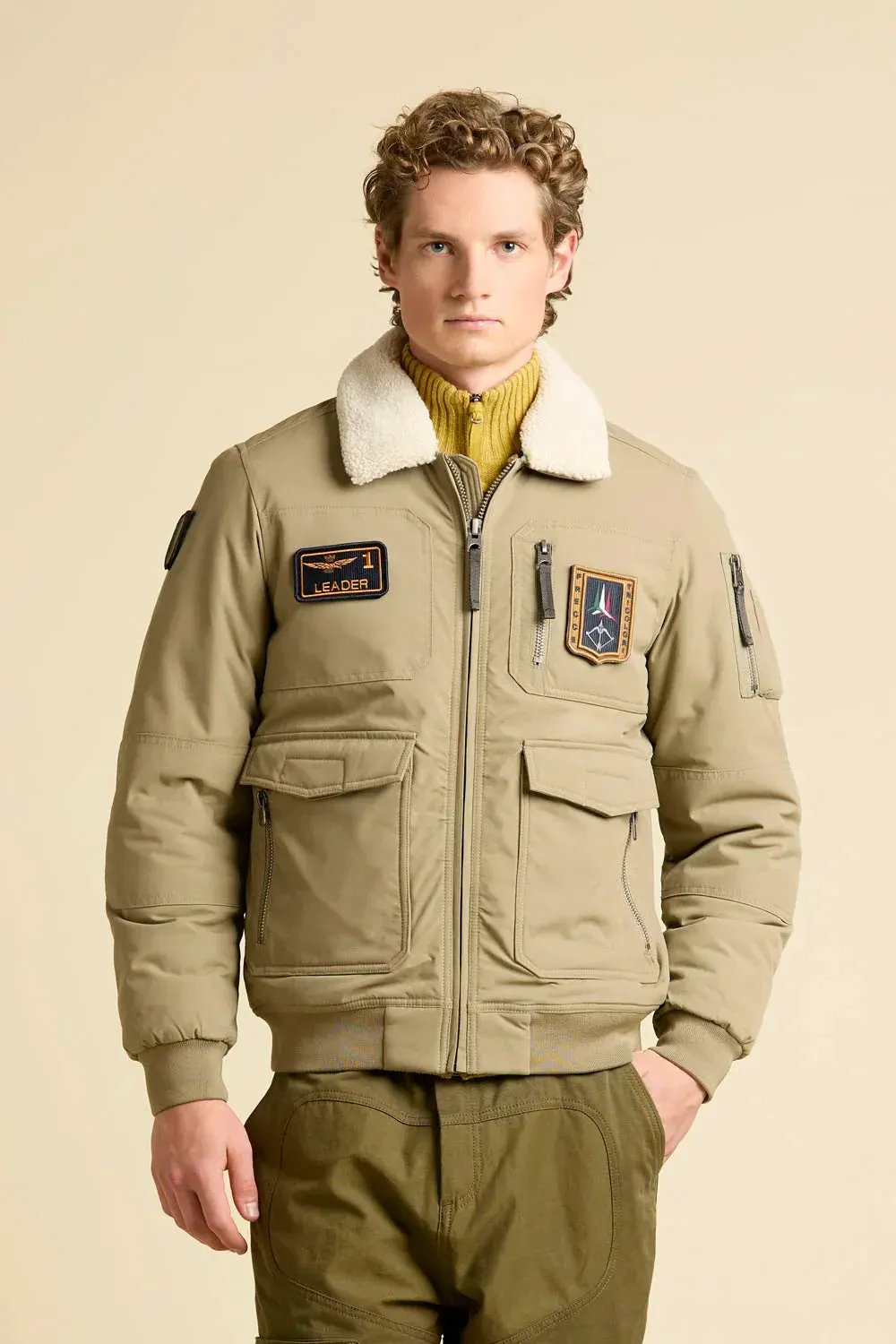 Giubbotto pilot beige con colletto in shearling e patch, moda uomo casual.