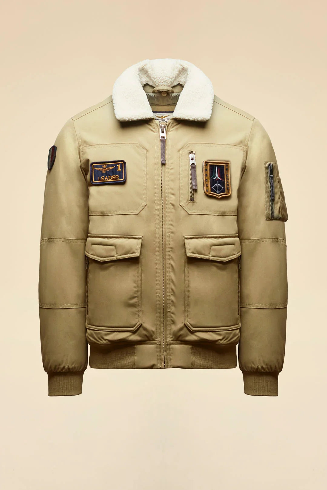 Giubbotto bomber beige da uomo con colletto in pelliccia e patch decorative stile aviatore.