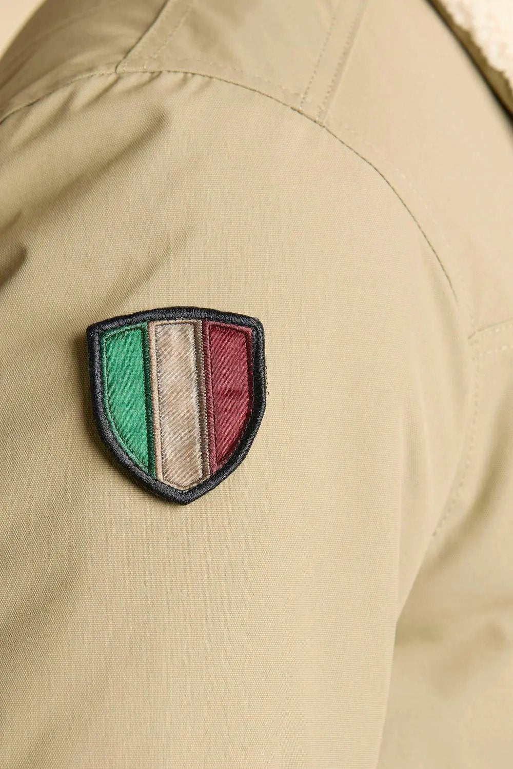 Dettaglio giubbotto beige con patch tricolore, stile pilot, moda uomo alta qualità