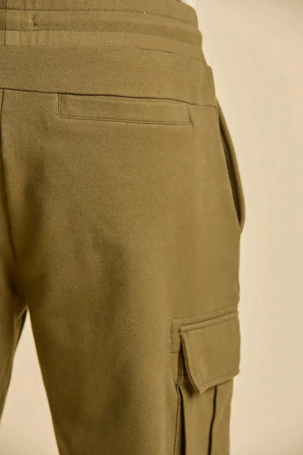 Dettaglio pantaloni cargo uomo felpa cotone verde oliva, tasca laterale e posteriore.