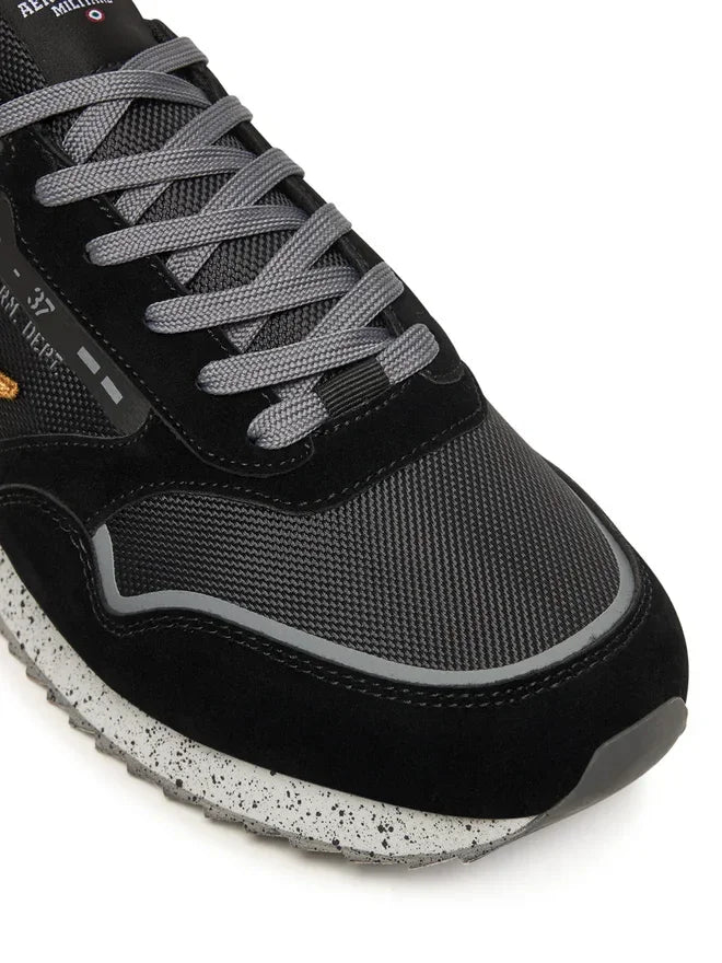 Sneaker nera da uomo con dettagli in tessuto tecnico, suola bianca maculata e lacci grigi.