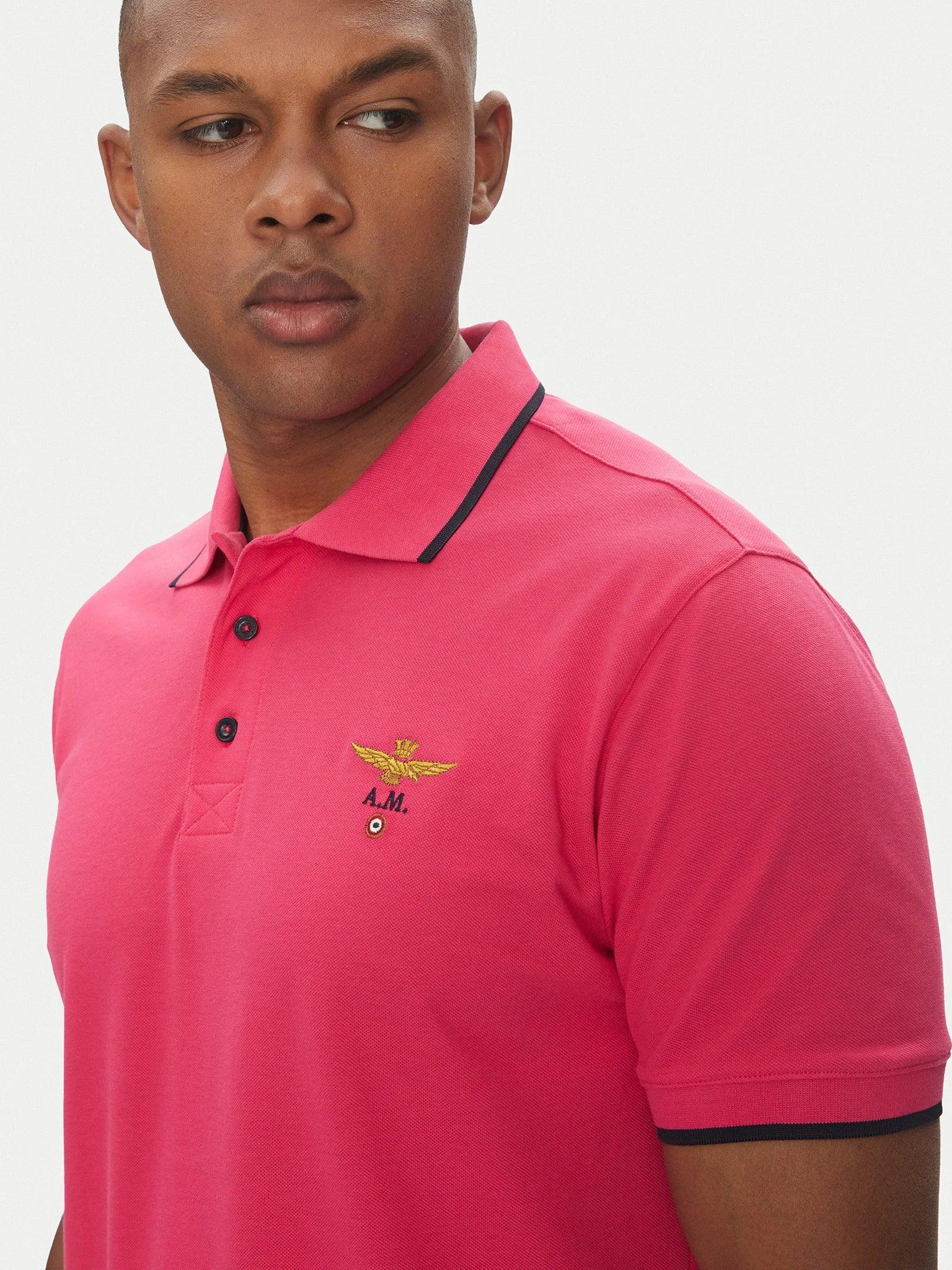 Uomo con polo magenta in cotone, dettagli neri e logo ricamato sul petto, moda uomo.