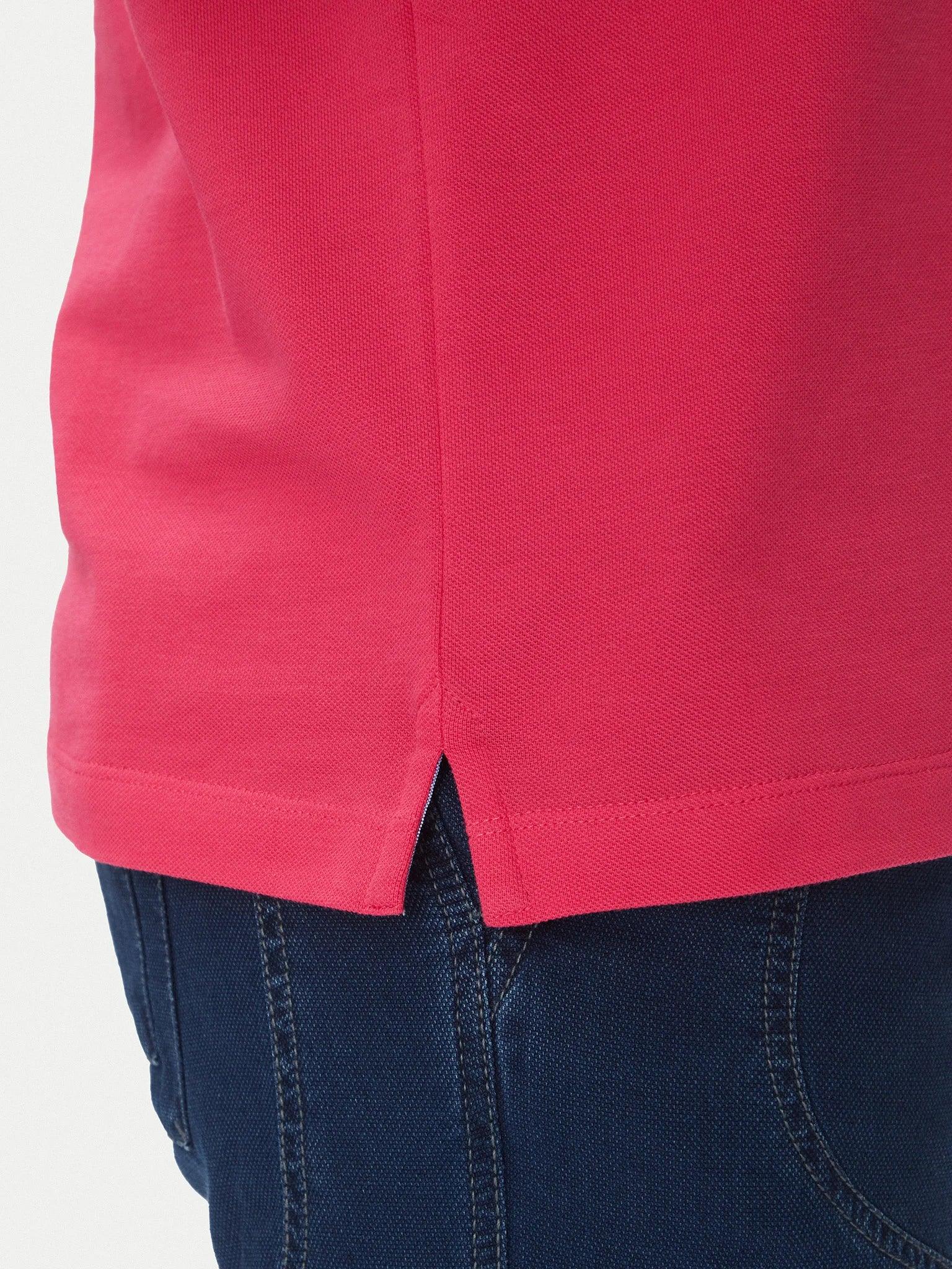 Dettaglio polo cotone magenta con spacchetto laterale indossata con jeans blu
