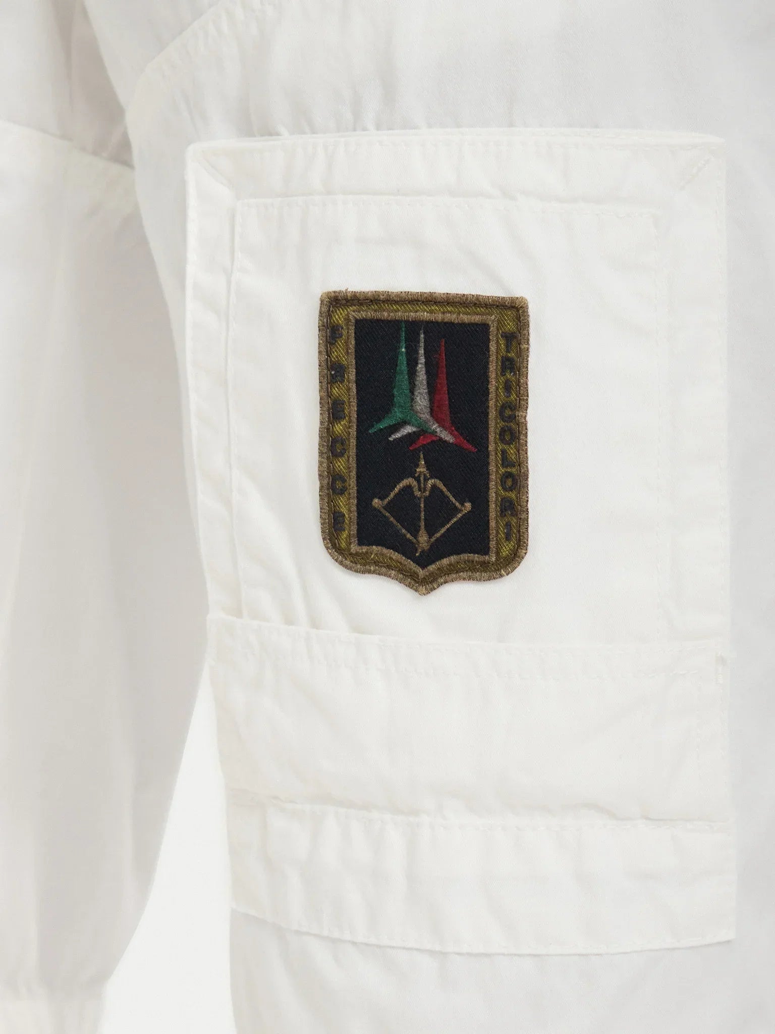 Dettaglio tasca pantaloncini bianchi uomo con patch ricamata tricolore e stemma militare.