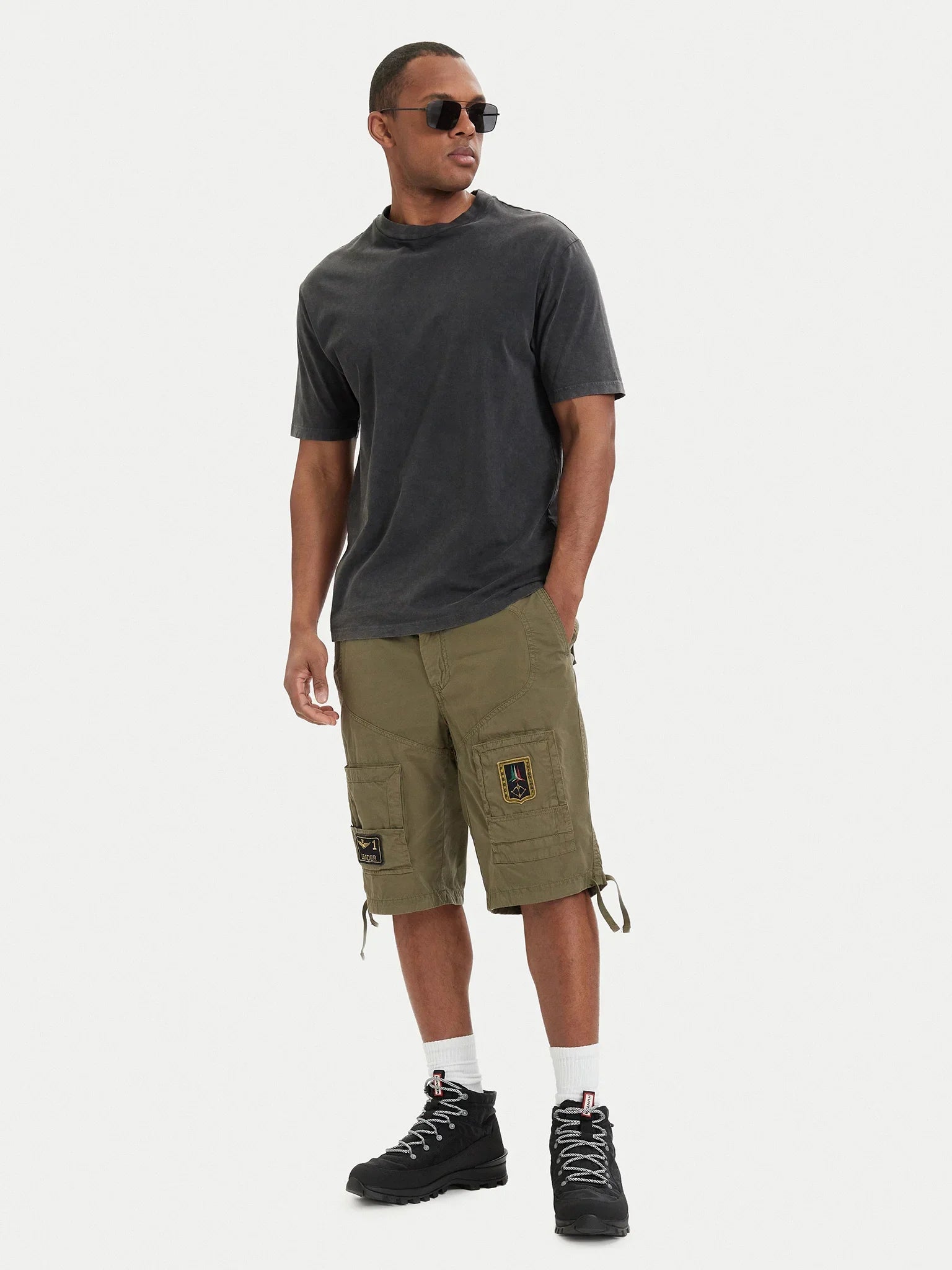 Uomo indossa pantaloncini cargo verdi regular fit con tasche e patch, stile casual