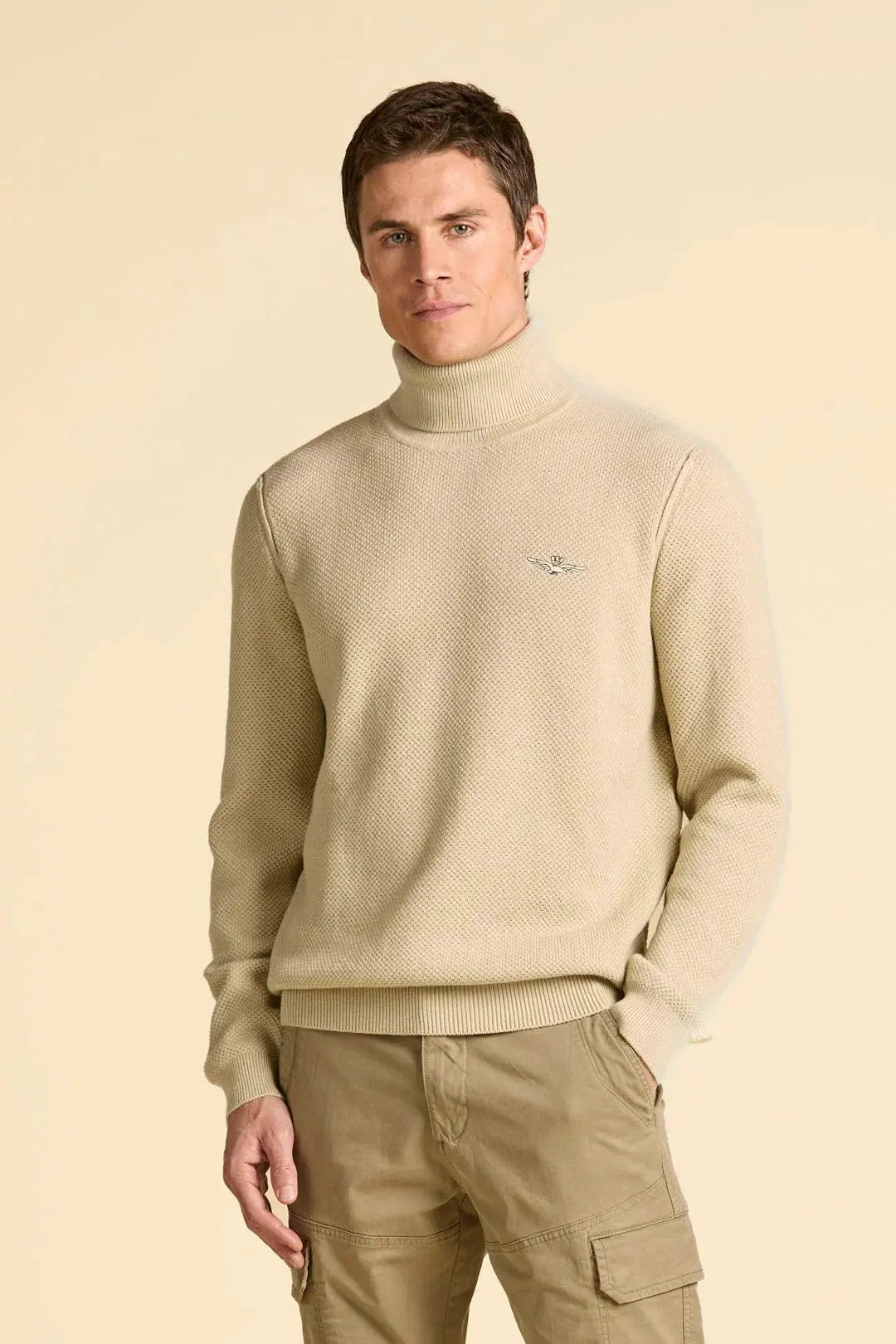 Maglione uomo beige a collo alto, lavorazione a maglia, look casual elegante.