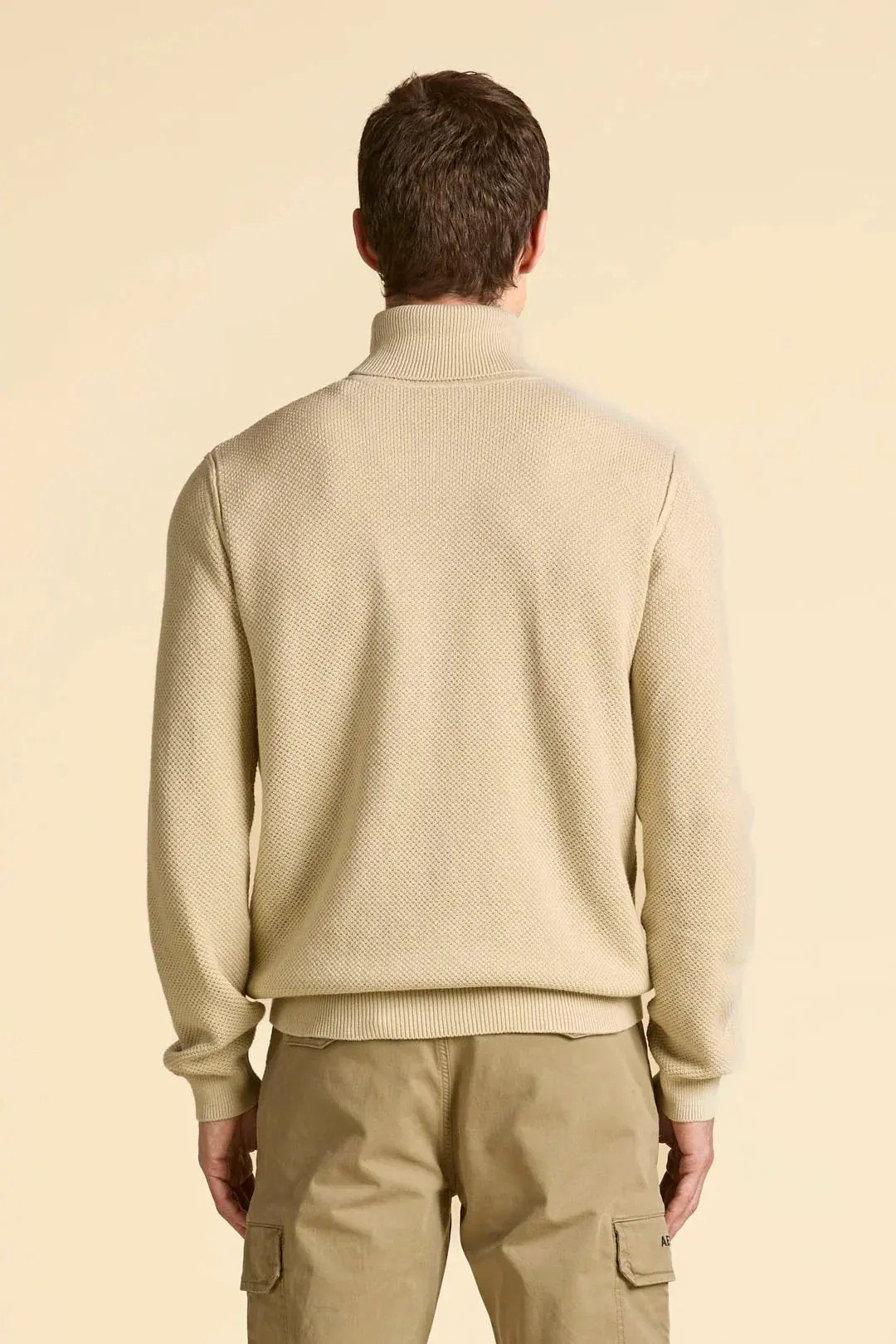 Maglione uomo beige collo alto lavorato, pantaloni cargo beige, vista posteriore