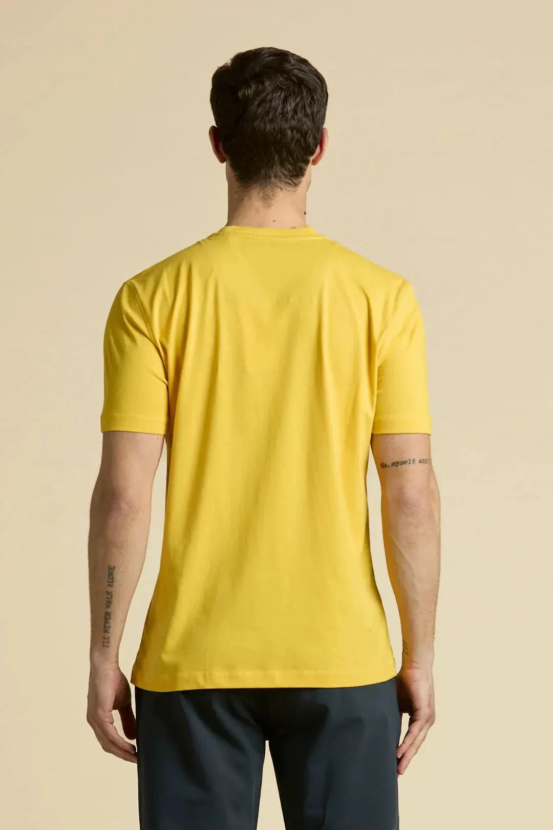 Maglietta uomo gialla a manica corta, vista posteriore, stile casual, fondo beige.
