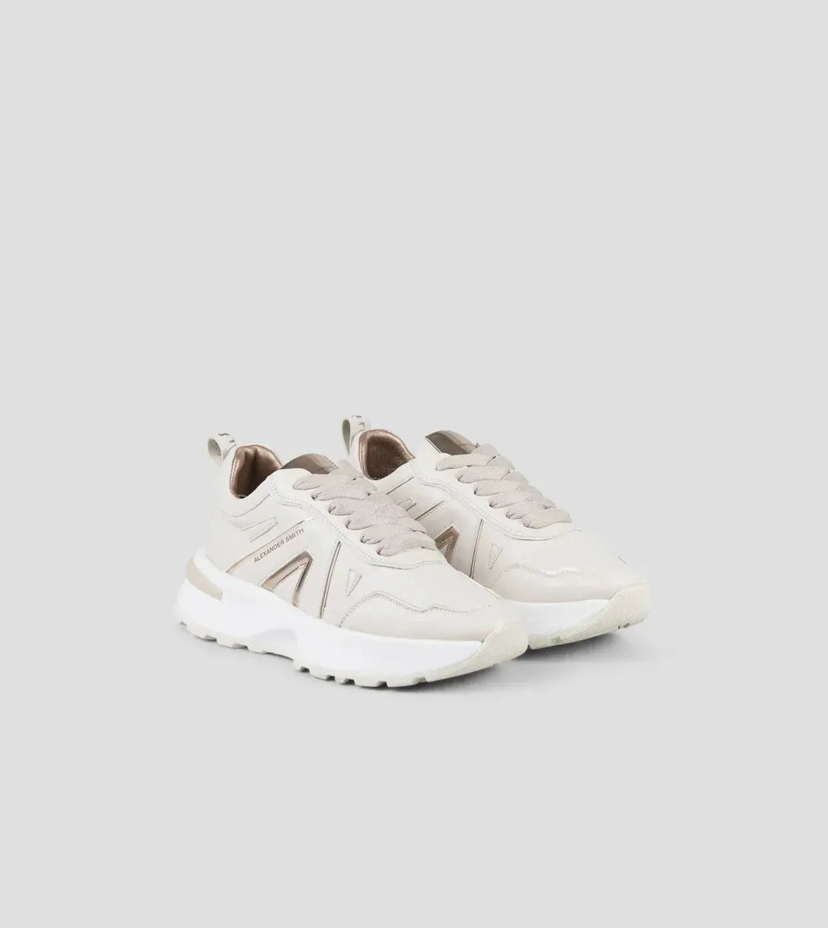 Sneakers donna beige rame con dettagli metallici, fondo chunky e design moderno su sfondo neutro.