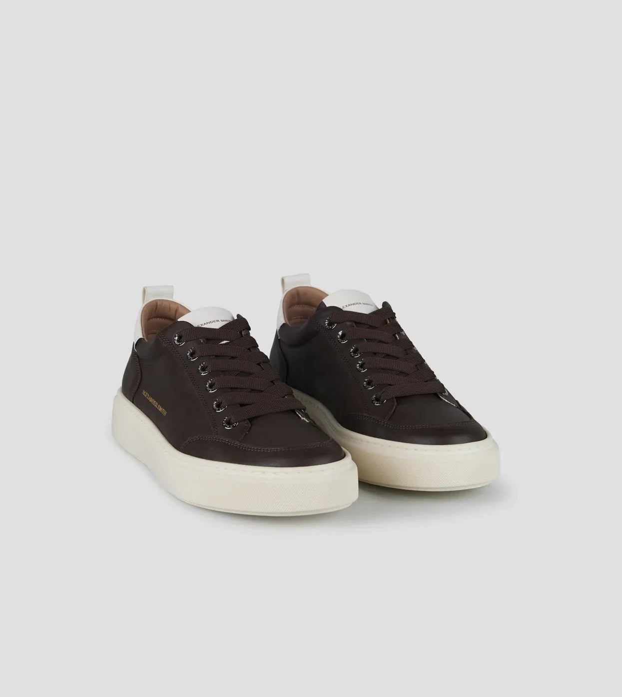 Sneakers uomo in pelle marrone scuro con suola bianca, lacci marroni, stile casual elegante.