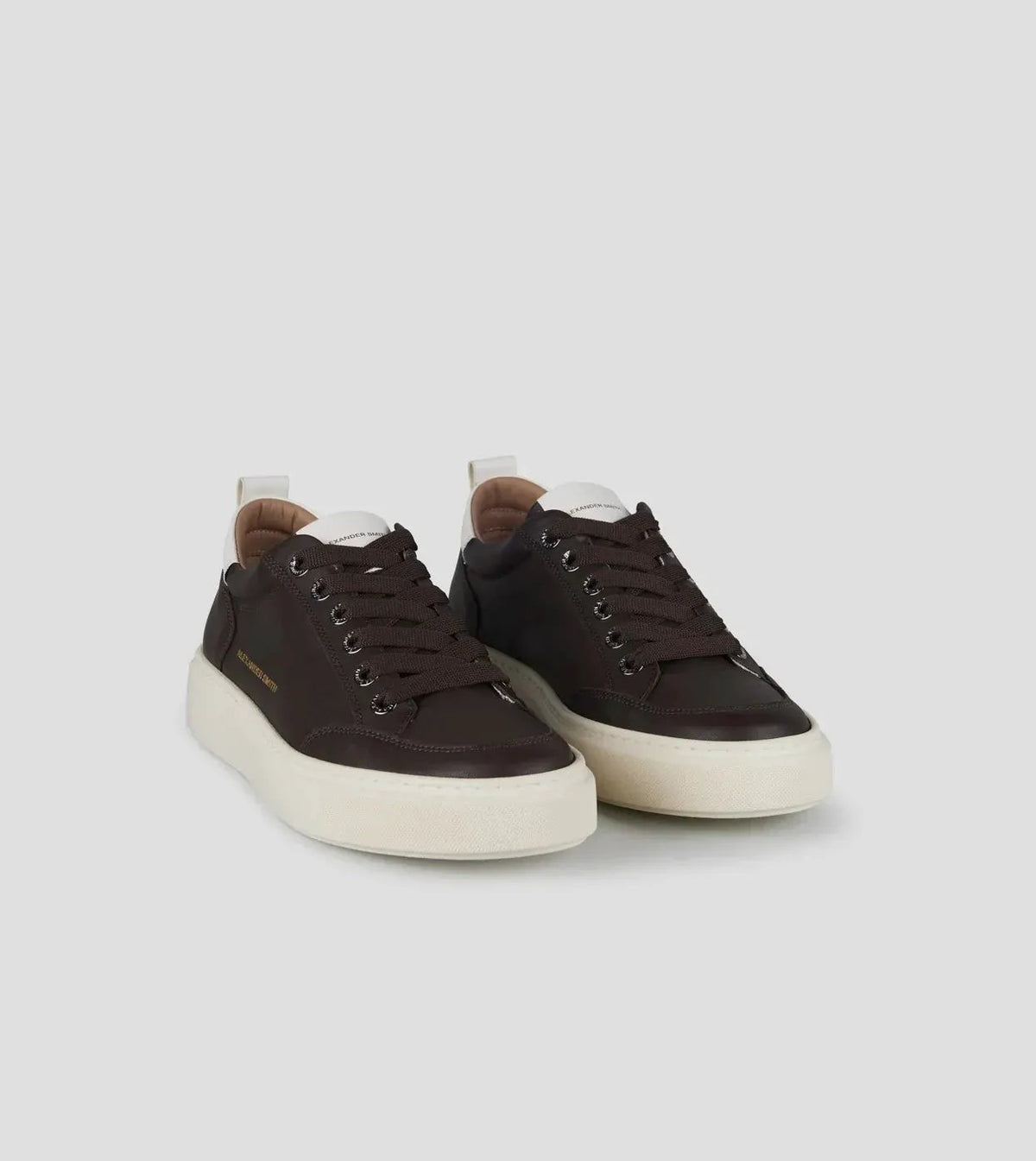Sneakers uomo in pelle marrone scuro con suola bianca, lacci marroni, stile casual elegante.