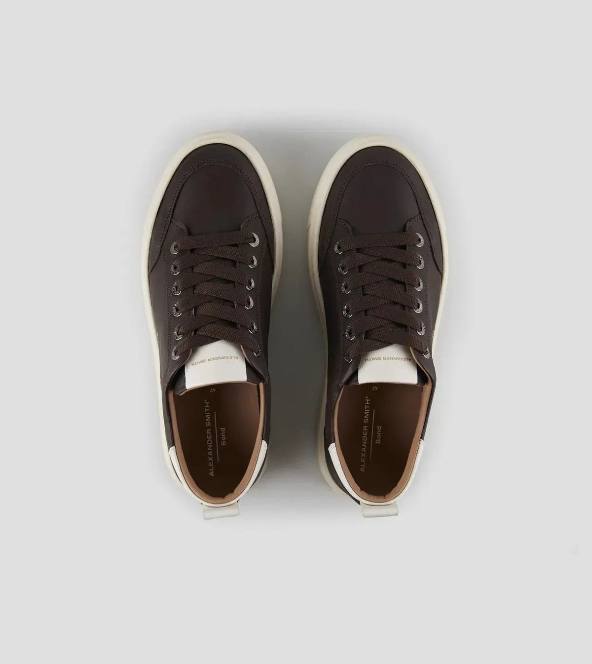 Sneakers uomo marroni con suola bianca, design moderno, lacci scuri, vista dall'alto.
