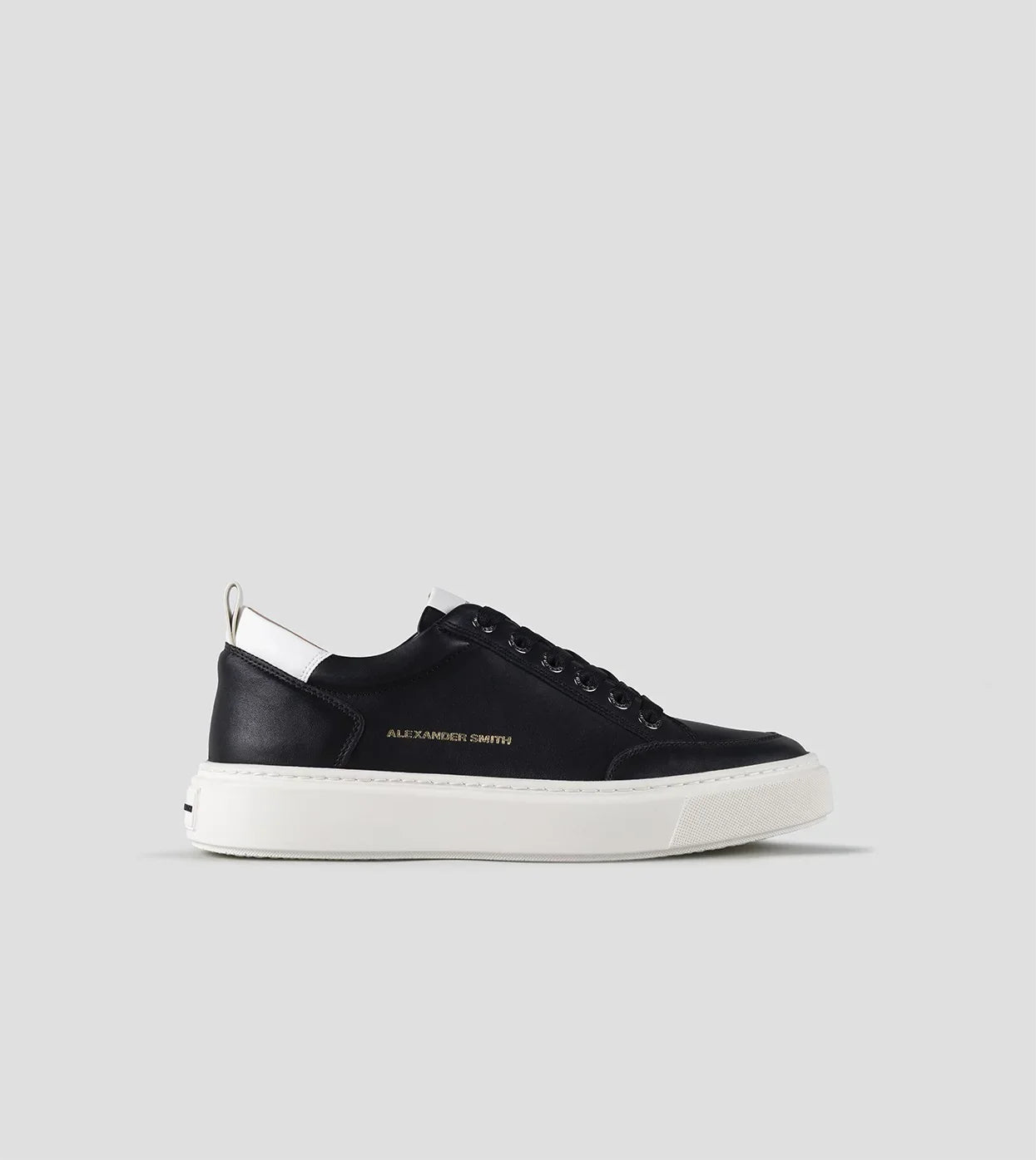 Sneaker uomo nera con suola bianca, dettagli bianchi e logo laterale dorato, stile casual.