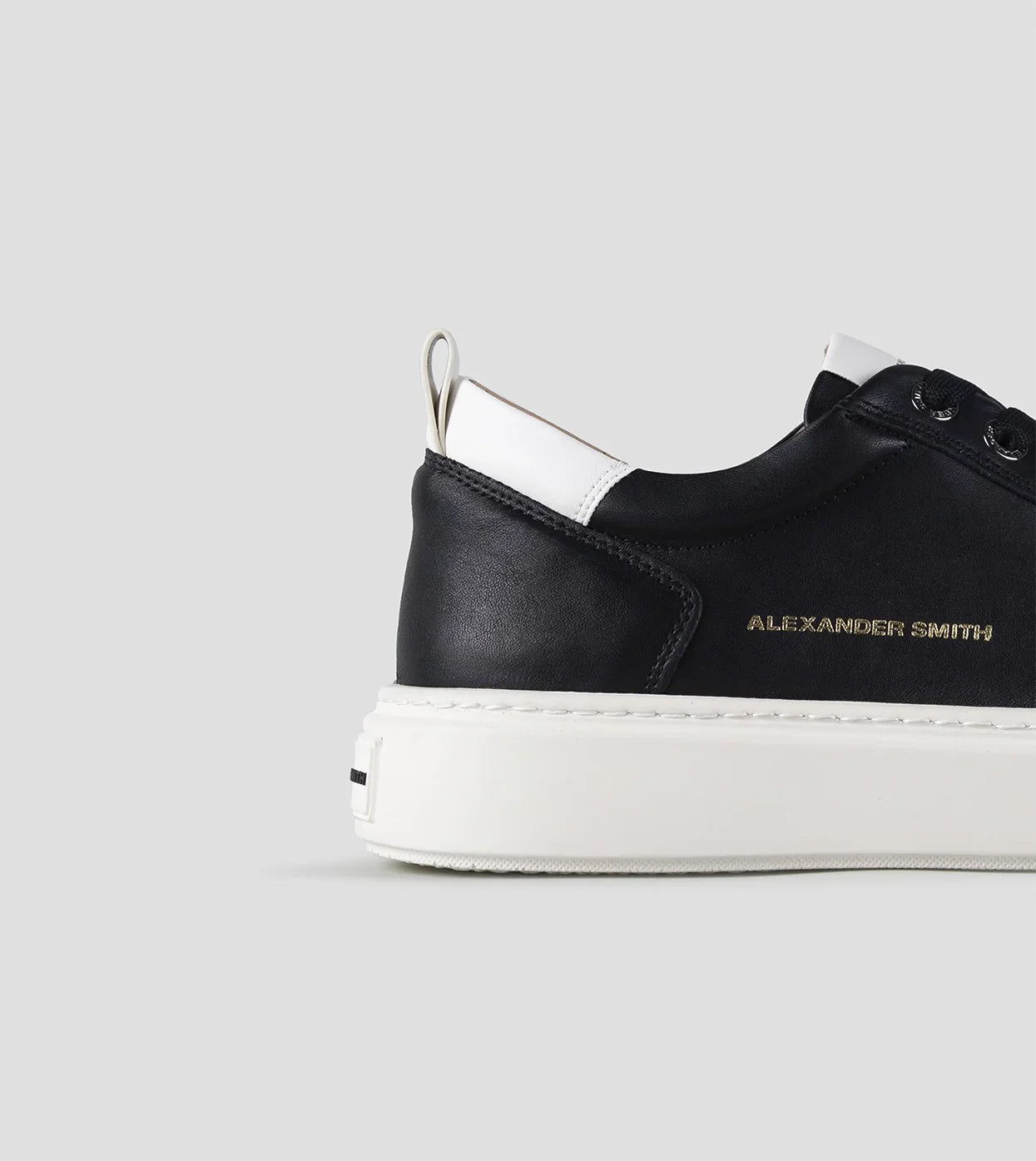Sneaker uomo nera e bianca in pelle con suola bianca e dettaglio laterale dorato.