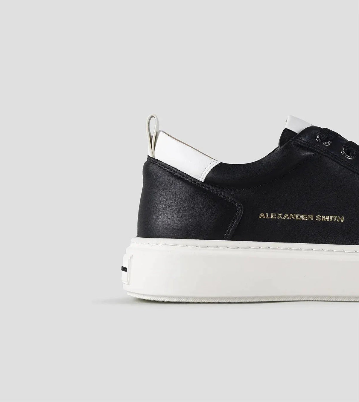 Sneaker uomo nera e bianca in pelle con suola bianca e dettaglio laterale dorato.