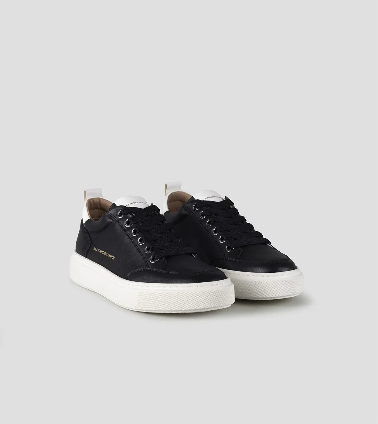 Sneakers uomo nere con suola bianca, dettagli logo dorato e tallone bianco, stile casual elegante.