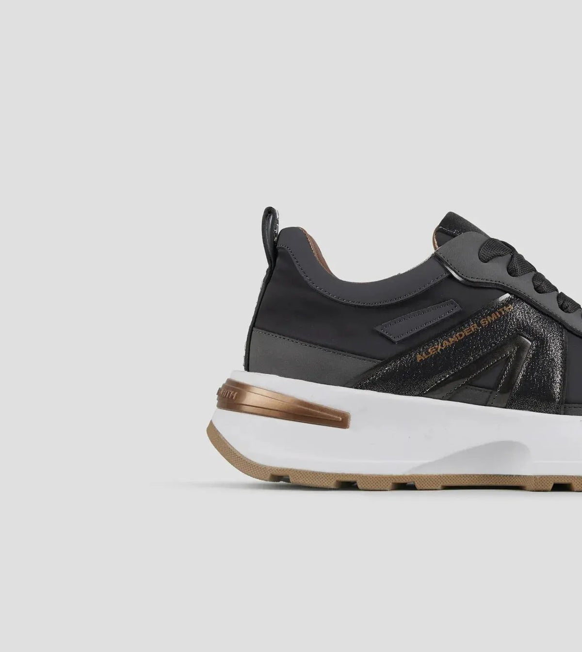 Sneaker donna nera con dettagli oro e suola alta bianca, fondo neutro, stile moderno