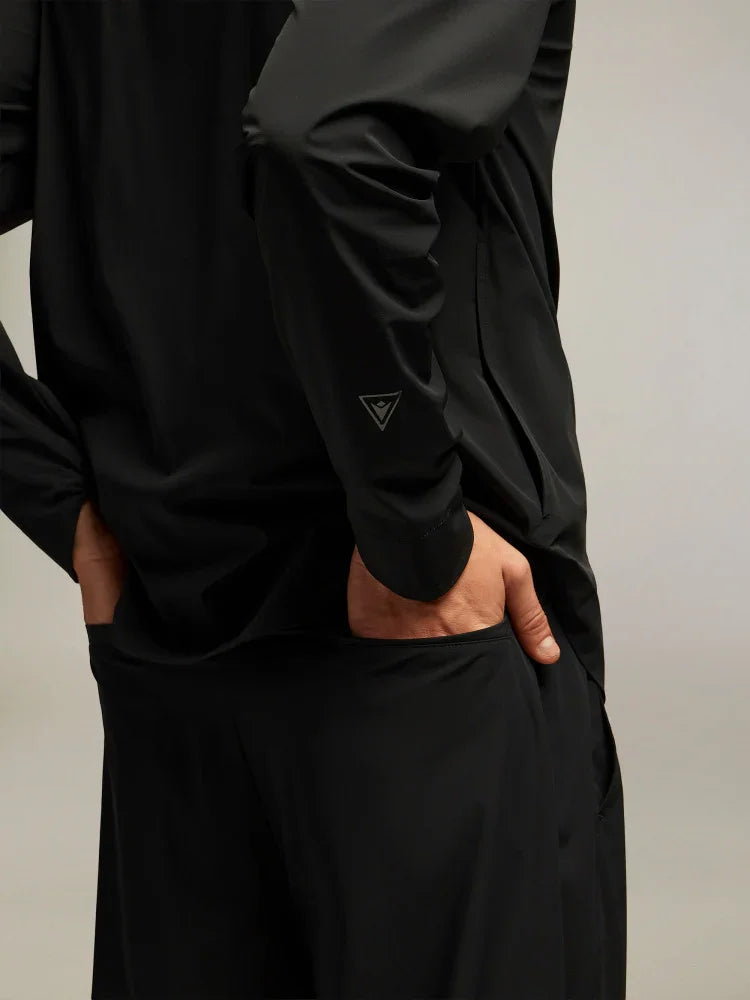 Dettaglio posteriore di giacca sportiva uomo nera, tessuto tecnico, mani nelle tasche.
