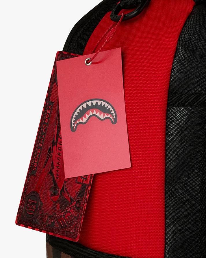 Zaino rosso con etichetta rossa decorata da mascella di squalo, dettaglio tessuto