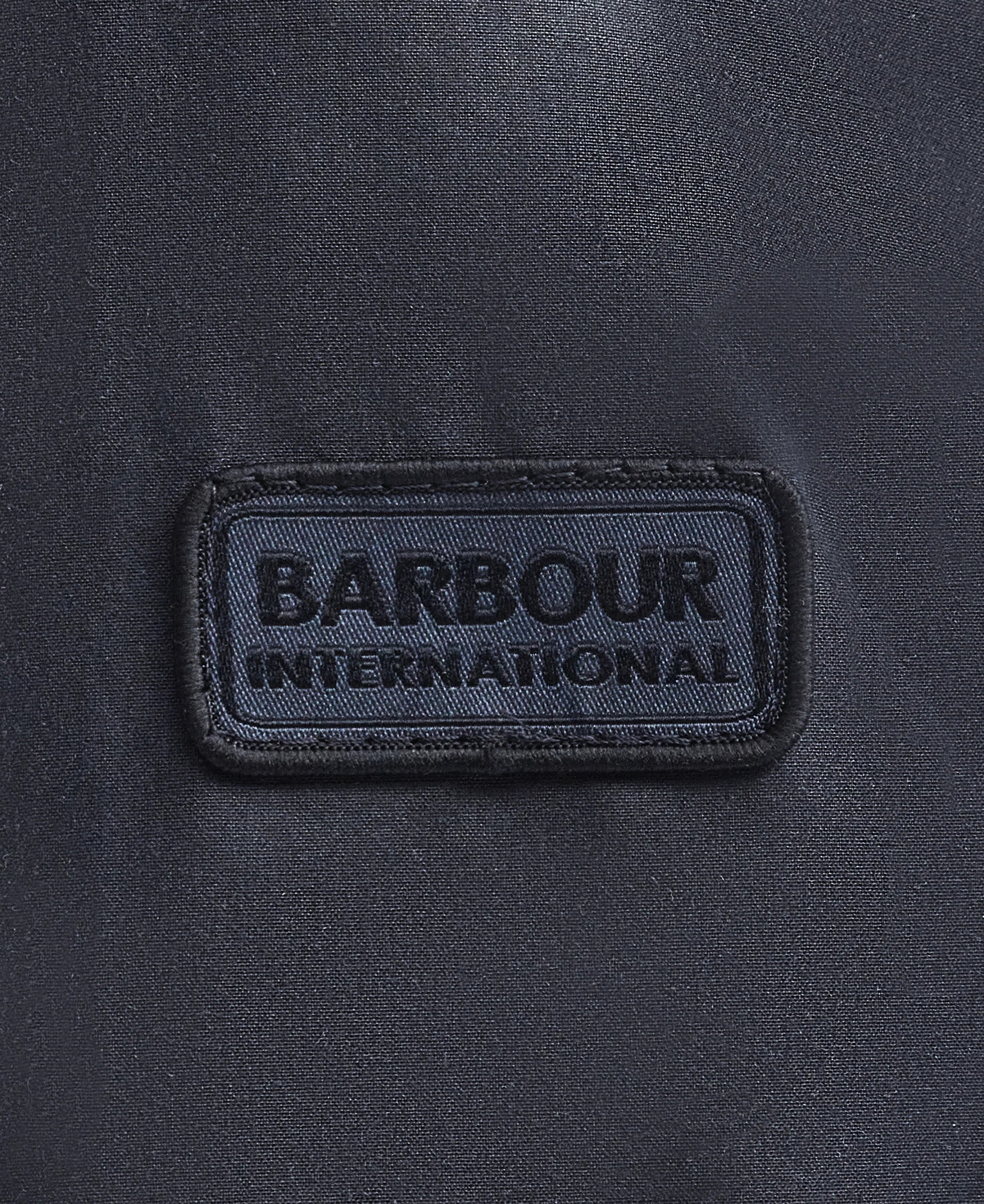 Dettaglio etichetta Barbour International su tessuto giacca cerata blu navy uomo
